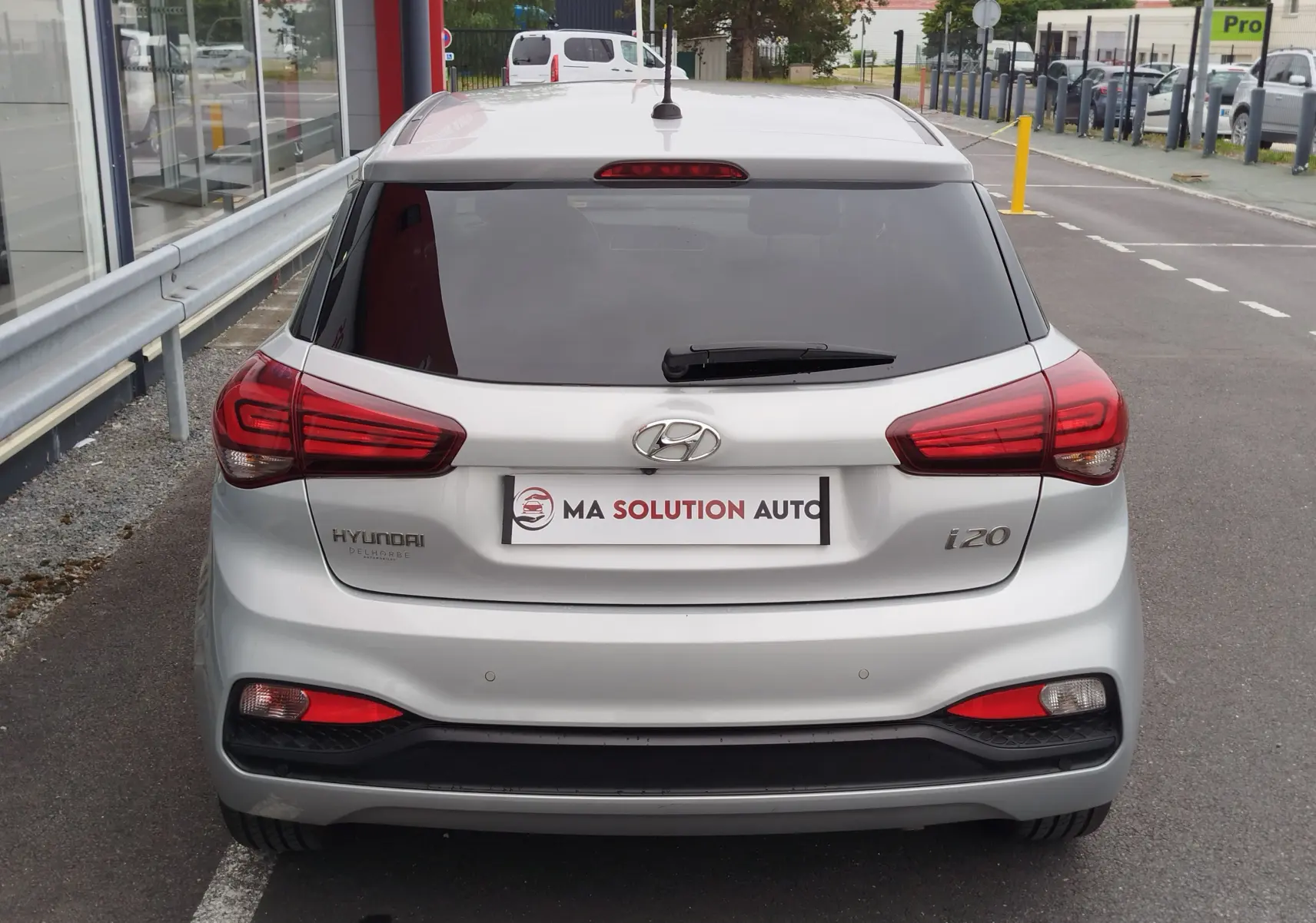 Vue arrière d'une Hyundai i20 2018 couleur Sleek Silver Métal avec feux rouges et lunette arrière teintée.