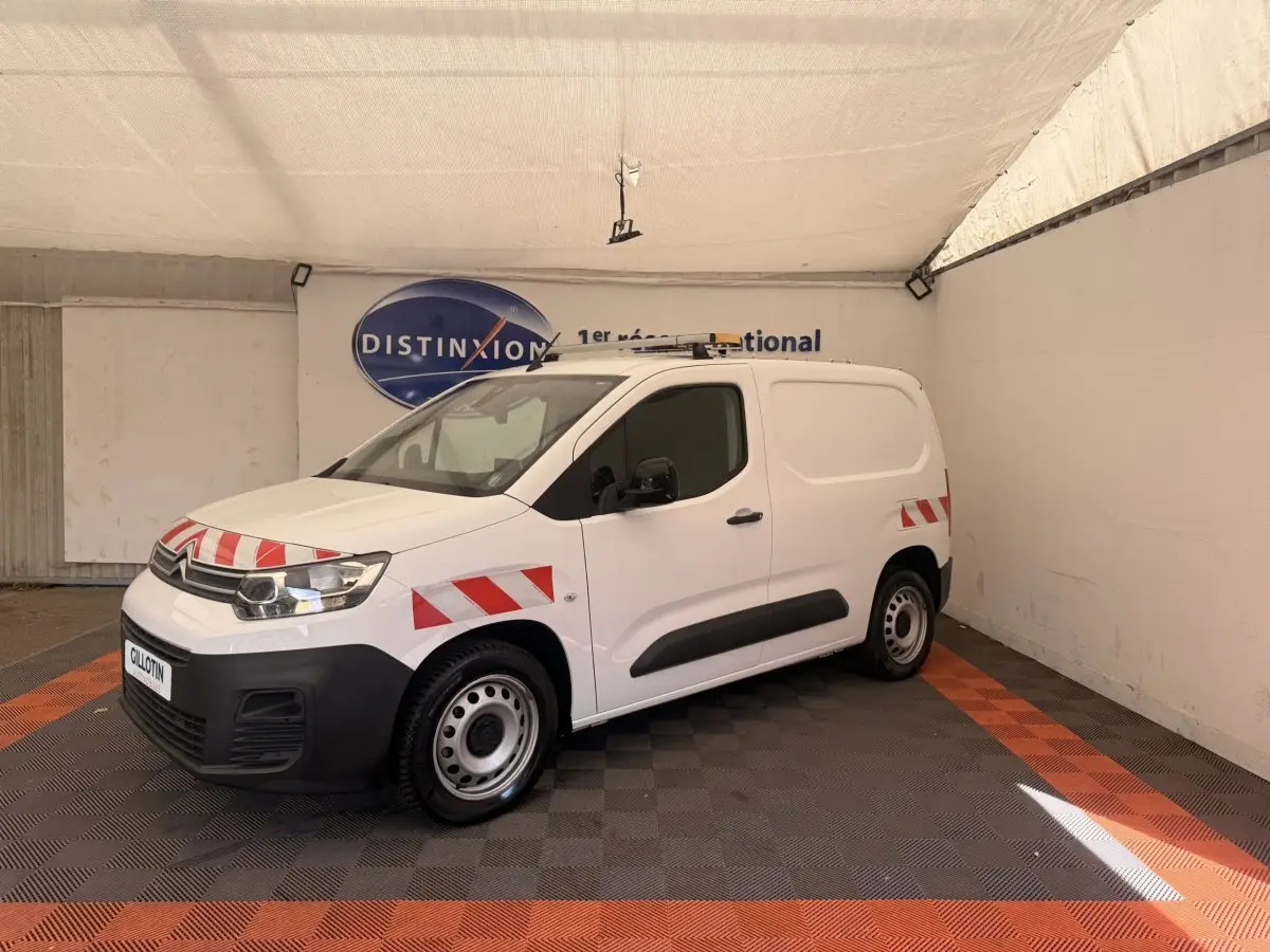 Fourgon Citroën Berlingo blanc en 3/4 avant gauche avec bandes rouges réfléchissantes et jantes acier.