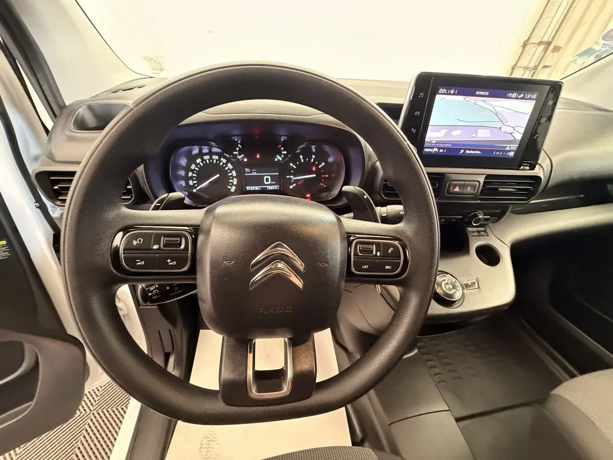 Vue intérieure centrée sur le volant Citroën d'un Berlingo blanc avec écran tactile et tableau de bord numérique.