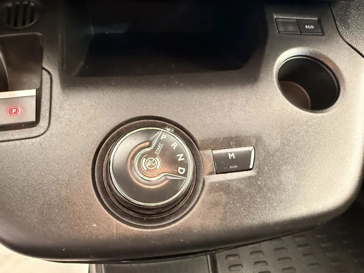Gros plan sur la commande rotative de la boîte automatique du Citroën Berlingo blanc, avec bouton mode manuel et frein électrique.