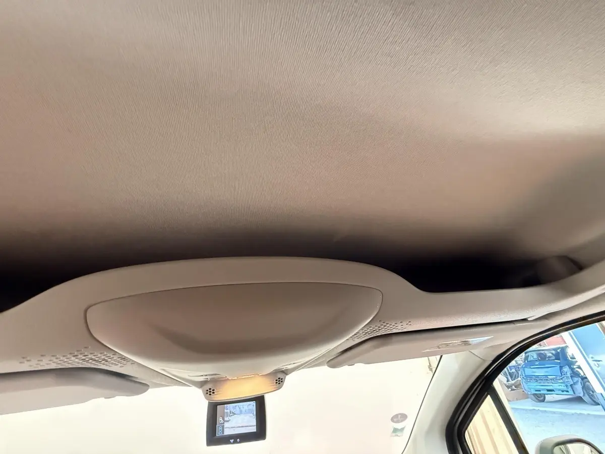 Vue intérieure du plafond avant beige du Citroën Berlingo blanc, avec miroir de surveillance et pare-soleil côté droit visible.