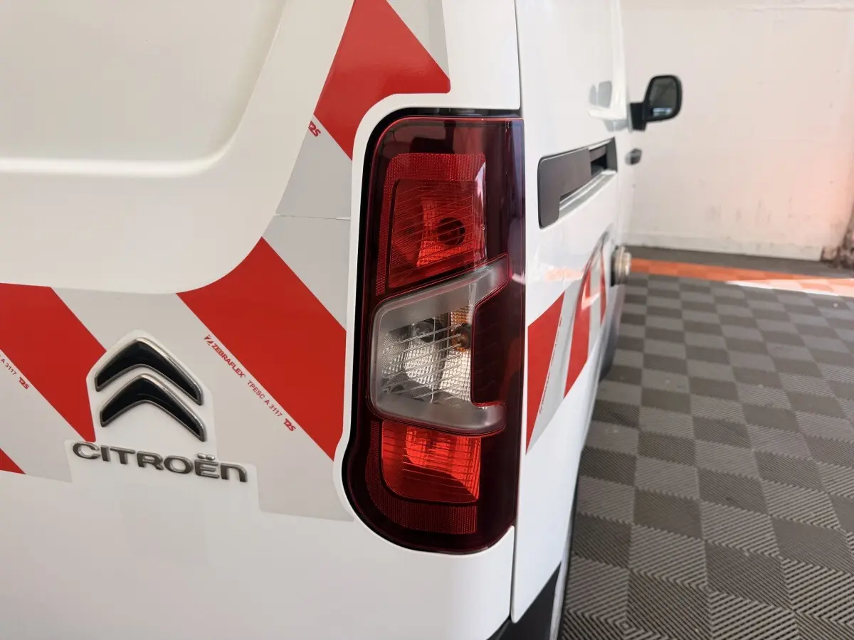 Gros plan sur l’arrière droit blanc du Citroën Berlingo 2022 avec bandes rouges de signalisation et feu arrière.