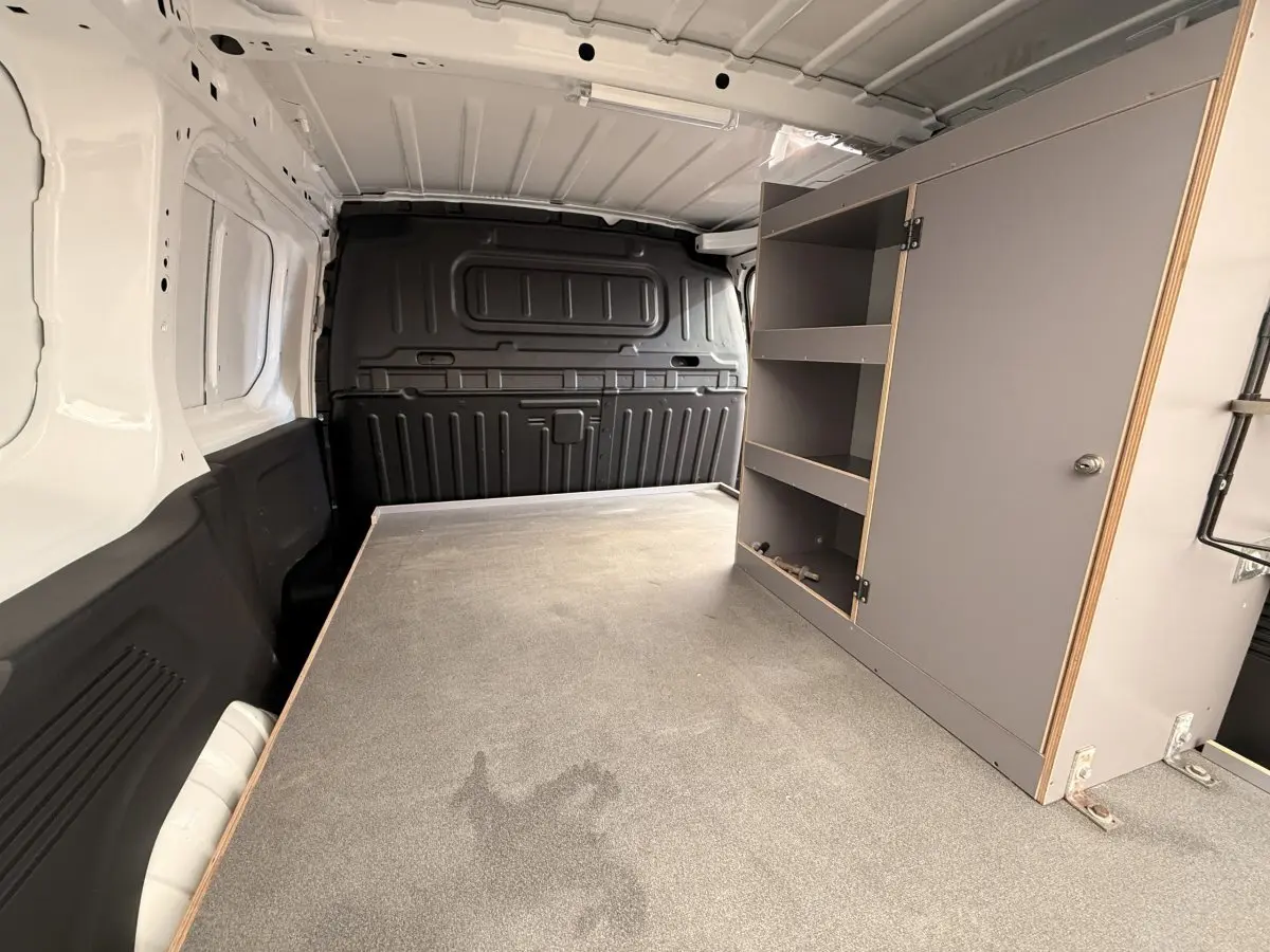 Vue intérieure arrière du Citroën Berlingo blanc avec cloison pleine et aménagement de rangement gris à droite.