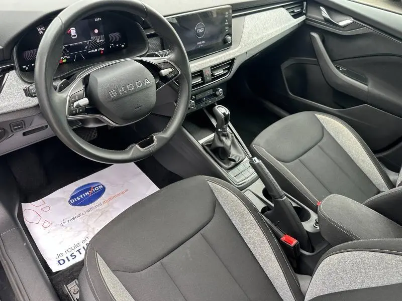 Vue intérieure avant droite du Skoda Scala blanc cristal 2025, avec volant cuir multifonction et sièges tissu noir/gris.