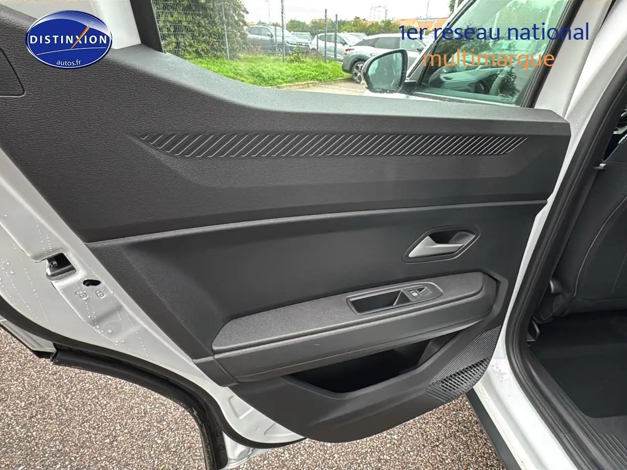 Porte arrière côté gauche ouverte du Dacia Duster blanc Arctic, montrant la garniture intérieure noire et la commande de vitre.
