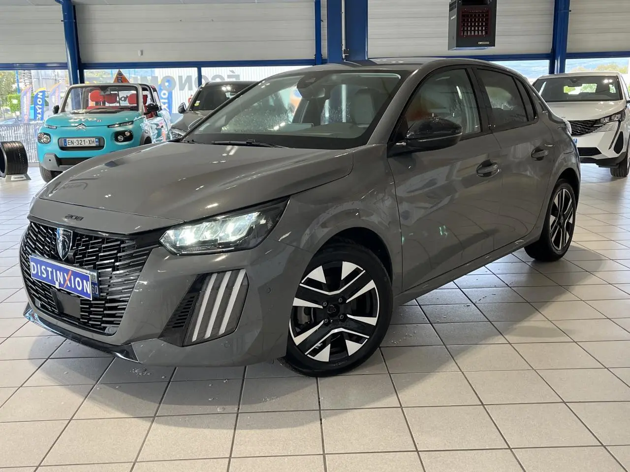 Peugeot 208 gris clair sélénium vue 3/4 avant droit avec calandre noire et jantes alliage bi-ton.