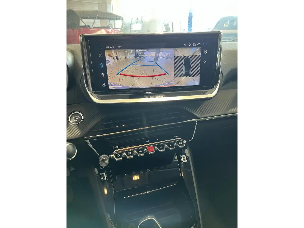 Vue rapprochée de la console centrale et écran tactile du Peugeot 208 1.2 essence gris clair Selenium, affichant la caméra de recul.
