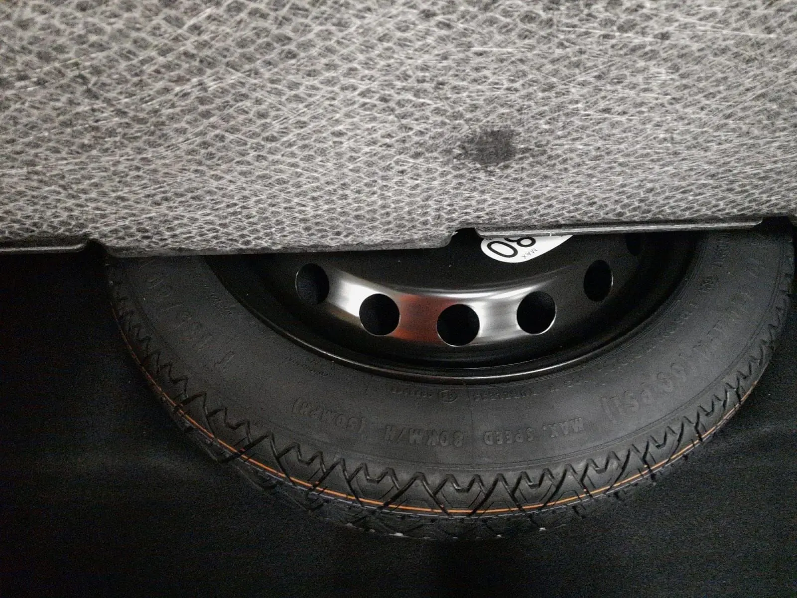 Gros plan sur la roue de secours temporaire noire sous le coffre du Renault Symbioz gris Casiopee.