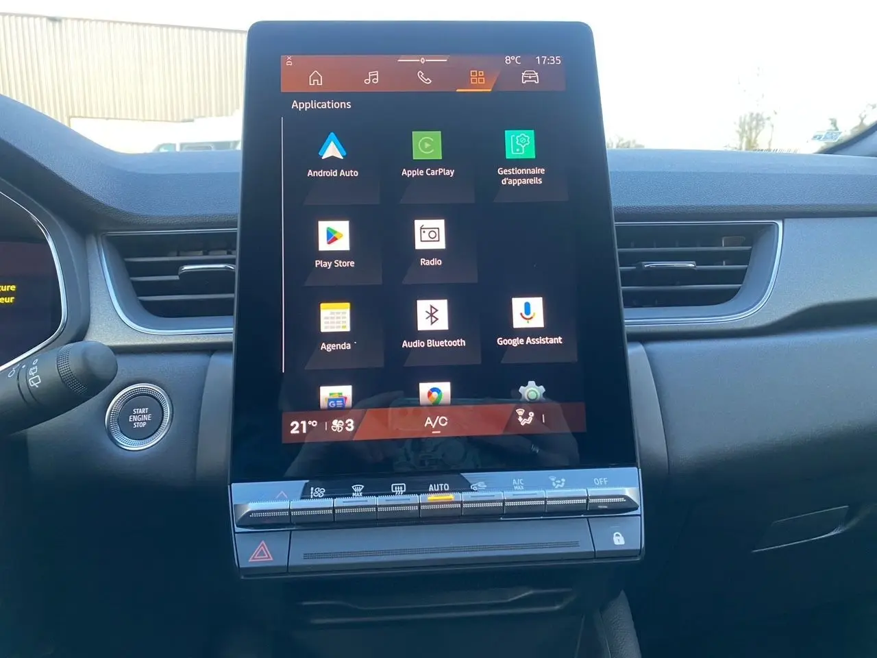Vue frontale du grand écran tactile central du tableau de bord du Renault Symbioz gris Casiopee, affichant les applications connectées.