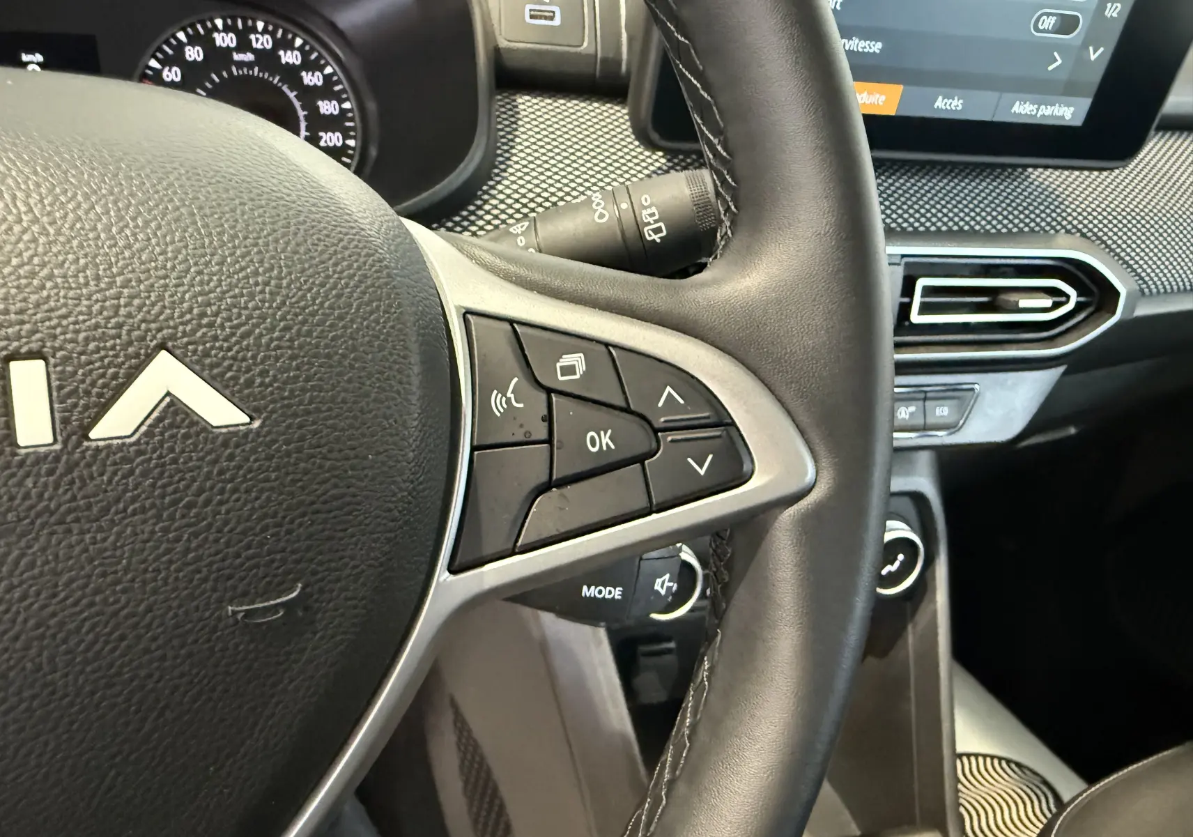 Vue rapprochée du volant côté droit de la Dacia Sandero gris 2025, avec commandes intégrées et tableau de bord partiel.