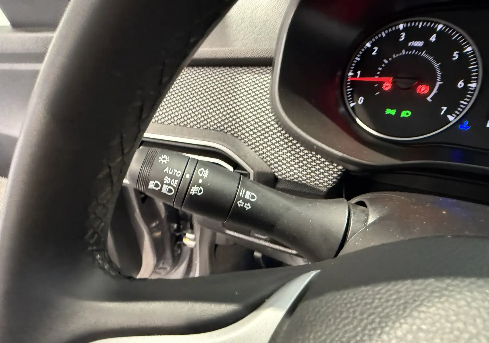 Gros plan sur la manette des feux et clignotants côté gauche du tableau de bord de la Dacia Sandero gris 2025.