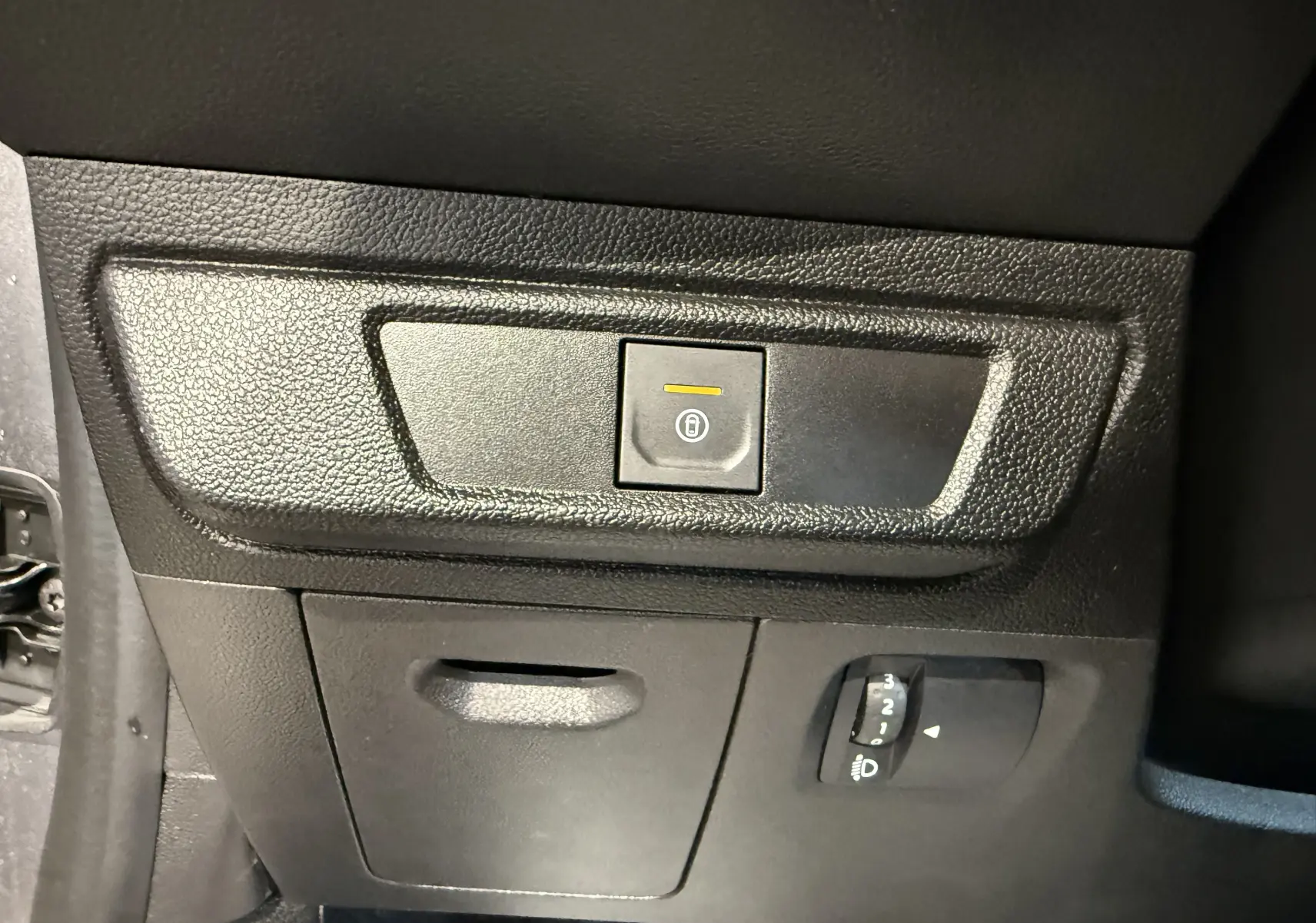 Détail du panneau de commande intérieur noir du Dacia Sandero 2025 avec bouton de verrouillage centralisé et réglage des phares.