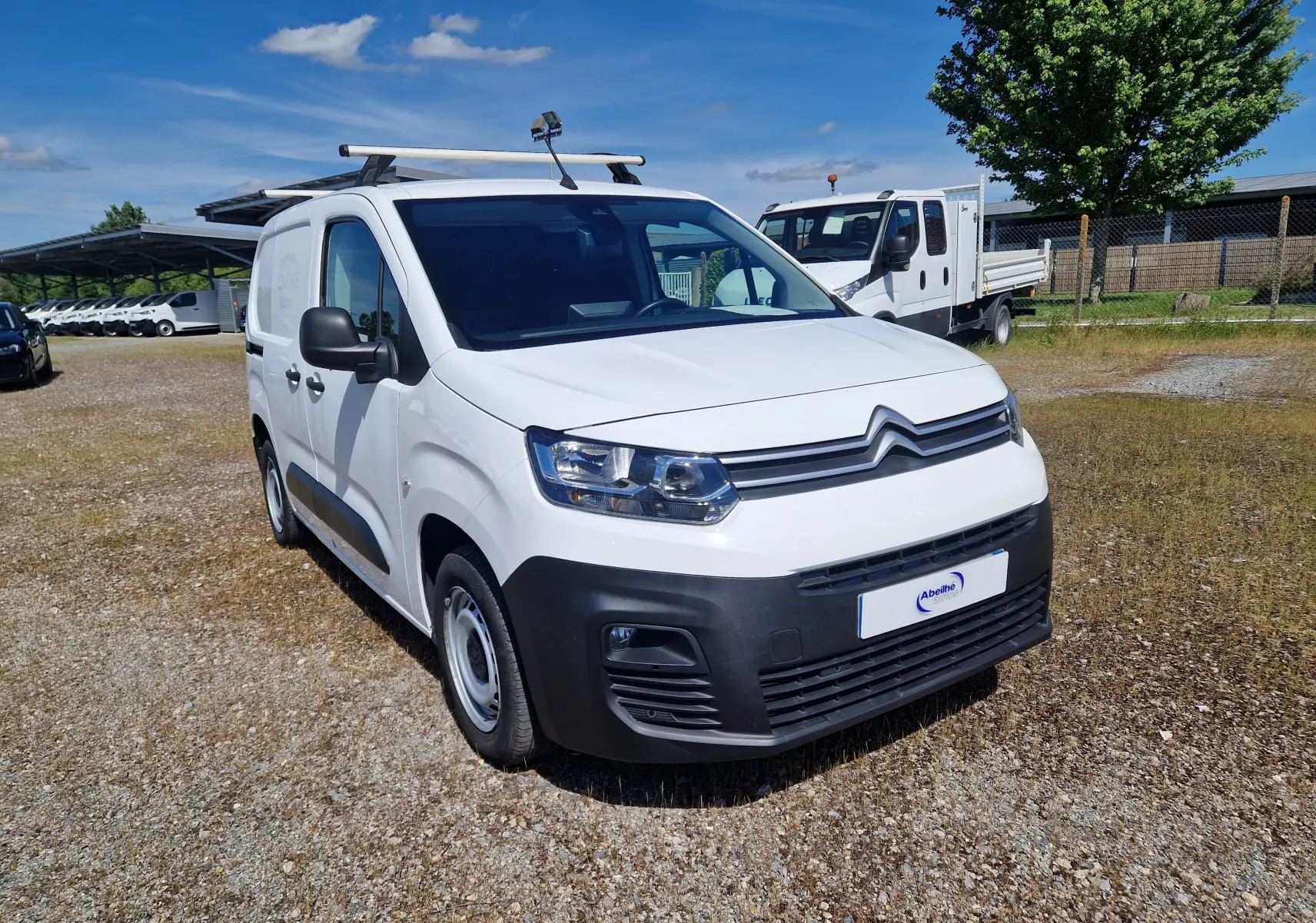 Vue 3/4 avant droit d'un Citroën Berlingo blanc 2020 utilitaire avec galerie de toit et pare-chocs noirs.