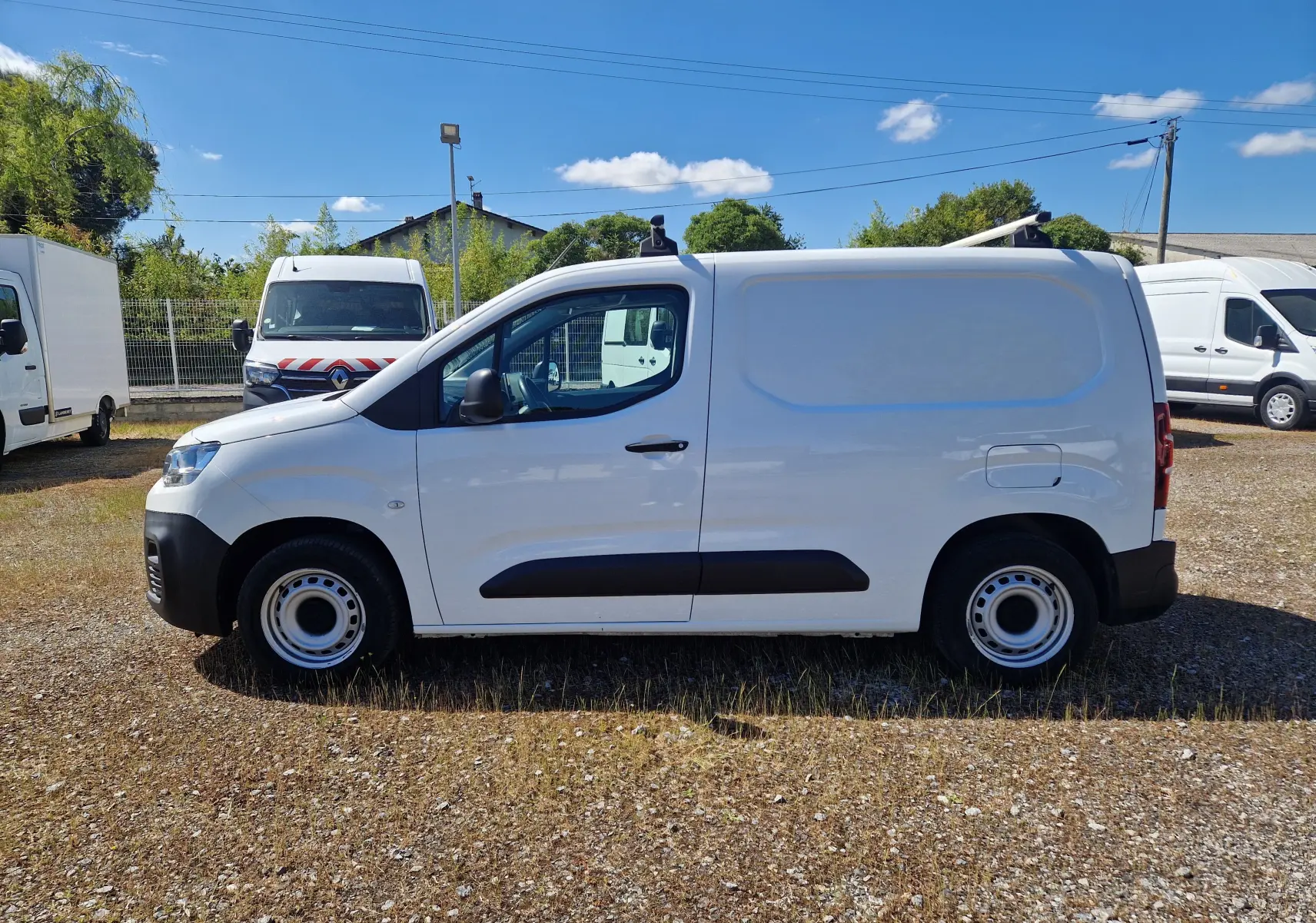Vue de profil côté gauche d’un Citroën Berlingo blanc utilitaire de 2020 avec barres de toit et jantes acier.