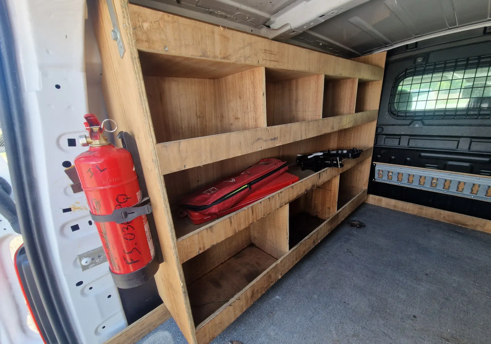 Intérieur arrière du Citroën Berlingo blanc 2020, vue côté gauche montrant étagères en bois et extincteur rouge fixé.