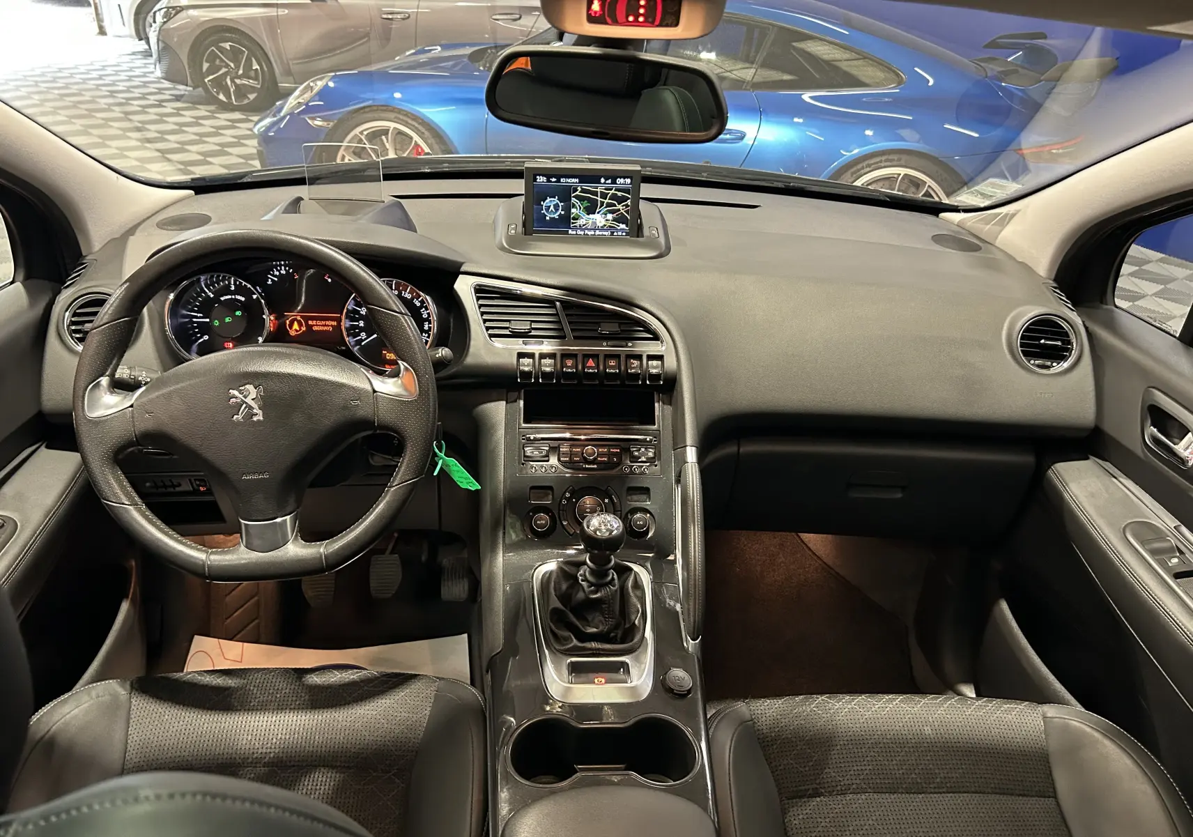 Vue intérieure frontale du Peugeot 3008 gris de 2015, montrant le tableau de bord, volant, boîte manuelle et écran central GPS.