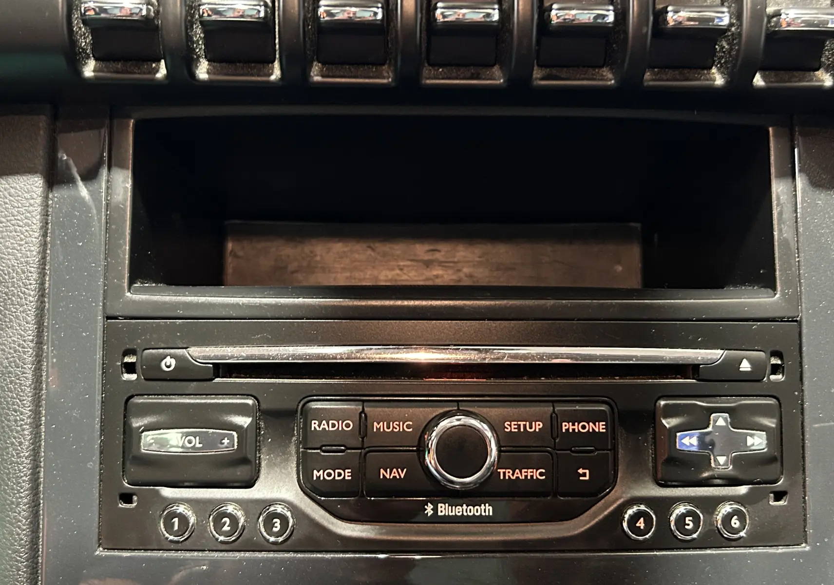 Gros plan sur la console centrale noire du Peugeot 3008 gris, avec commandes radio, navigation et Bluetooth visibles.