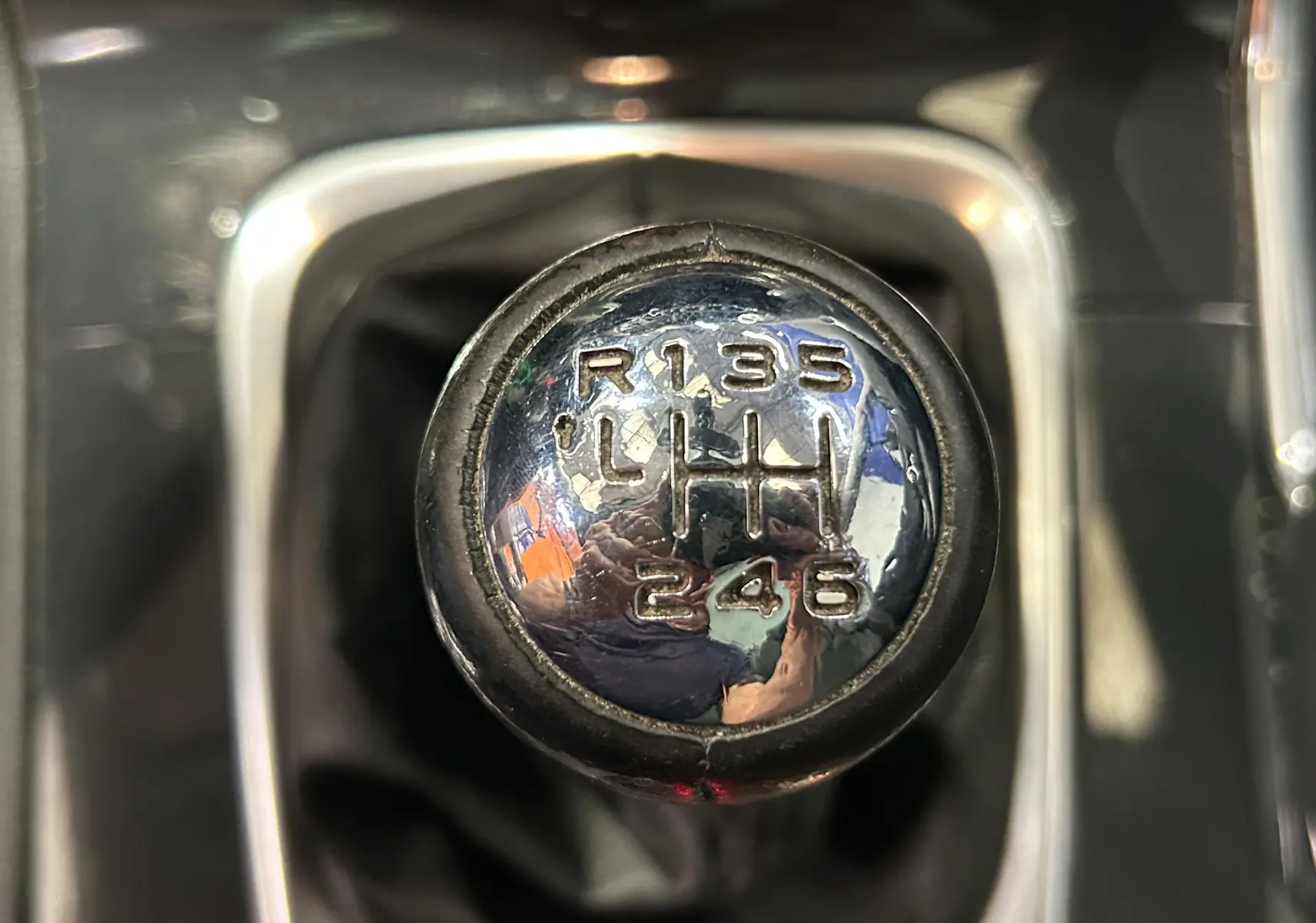 Gros plan sur le pommeau de levier de vitesse manuel chromé du Peugeot 3008 gris, montrant les six rapports et la marche arrière.