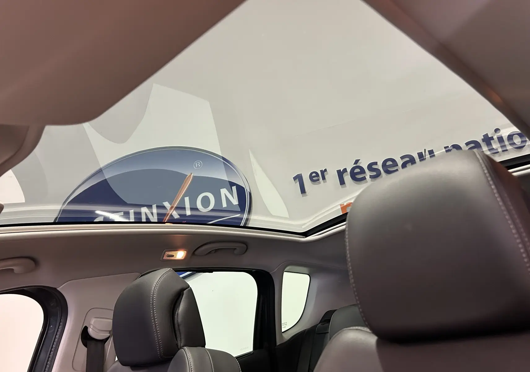 Vue intérieure du toit panoramique du Peugeot 3008 gris, avec sièges avant en cuir noir visibles de profil.