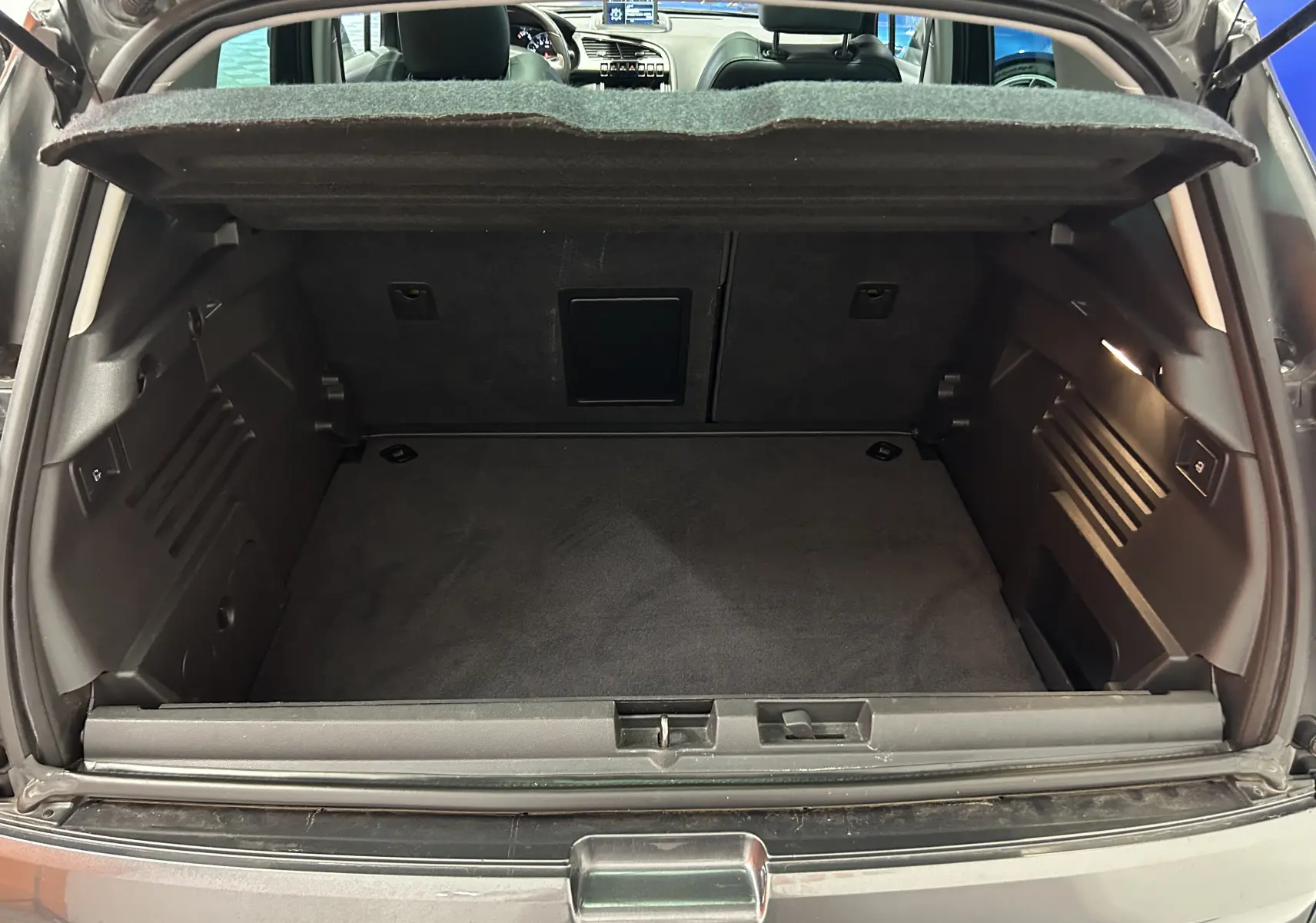 Coffre ouvert vu de l'arrière d'un Peugeot 3008 gris, montrant un espace de chargement propre et bien agencé.
