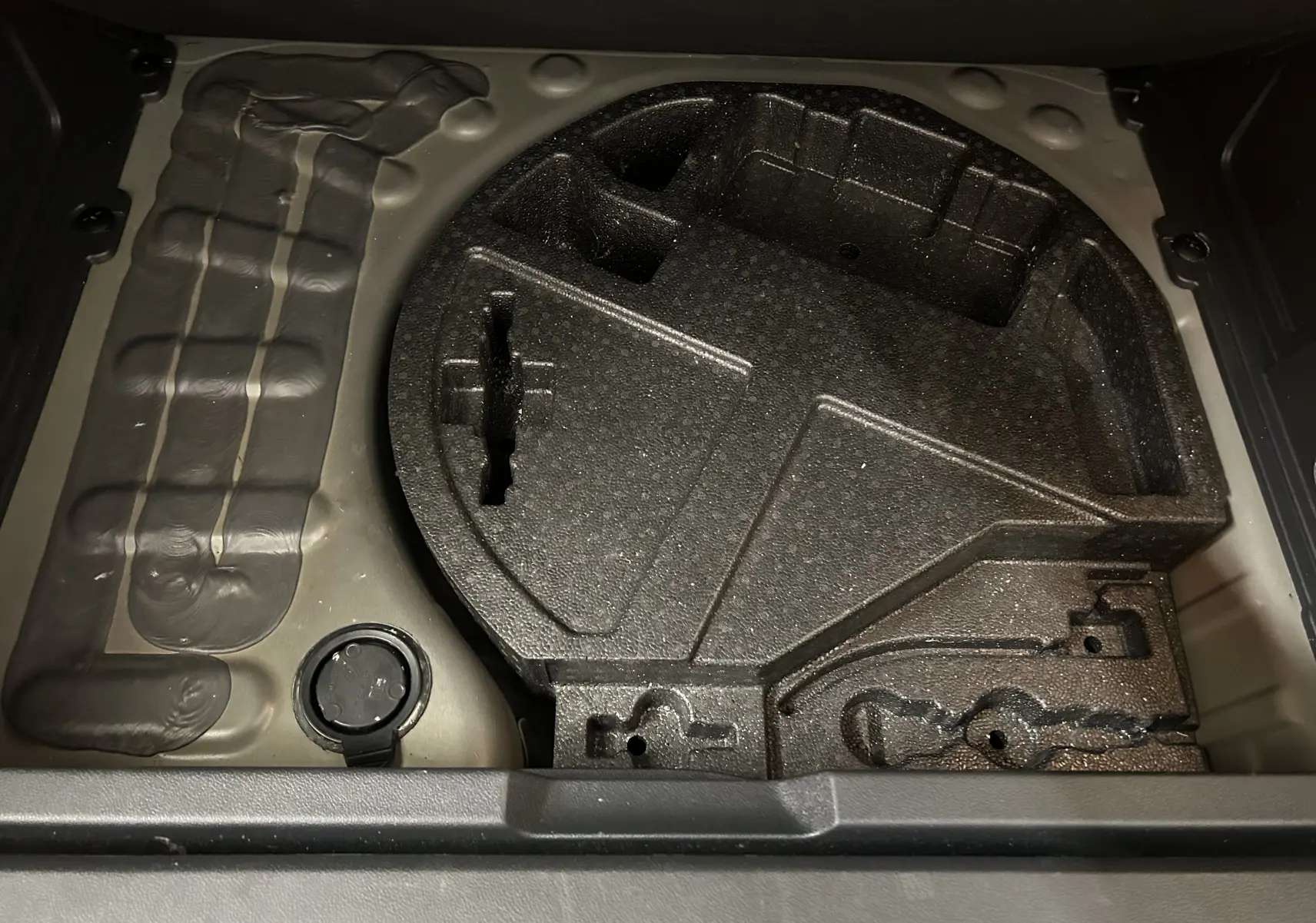 Coffre à outils vide dans le compartiment de roue de secours d'un Peugeot 3008 gris, vue de dessus.