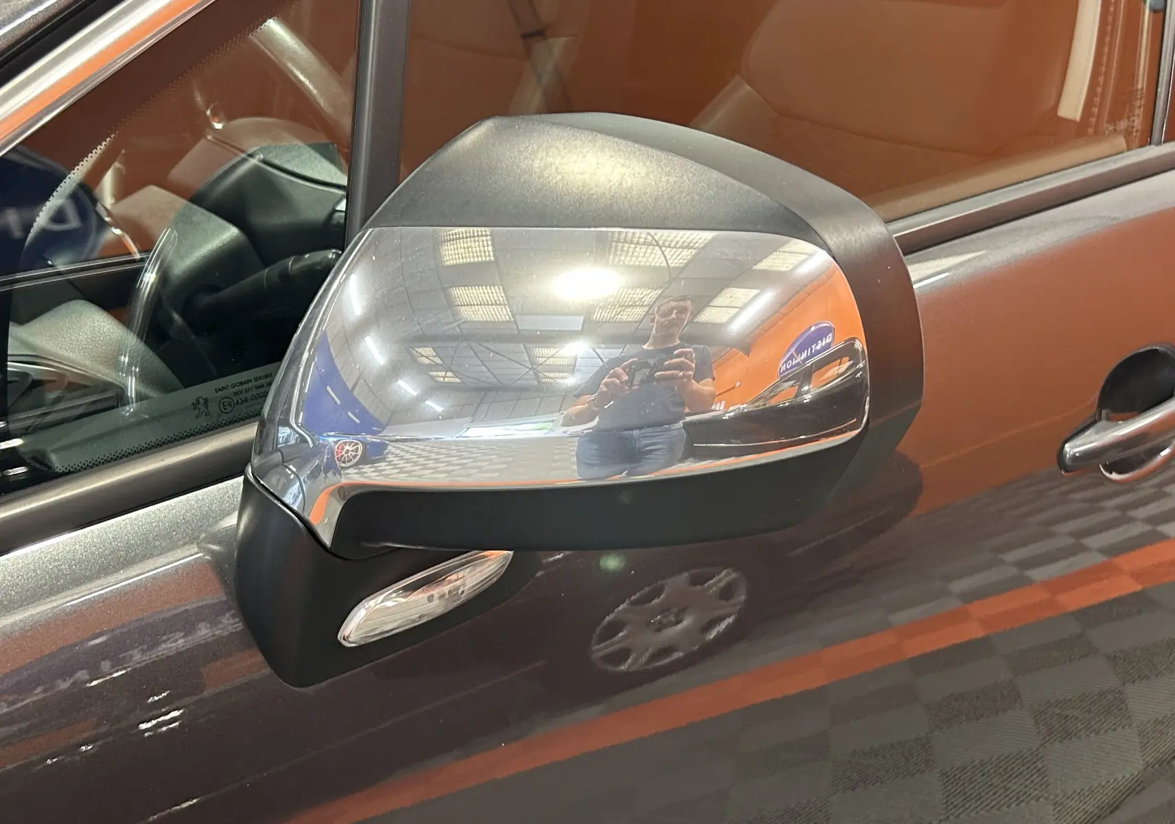 Gros plan sur le rétroviseur côté gauche chromé du Peugeot 3008 gris, avec reflet intérieur et environnement intérieur visible.