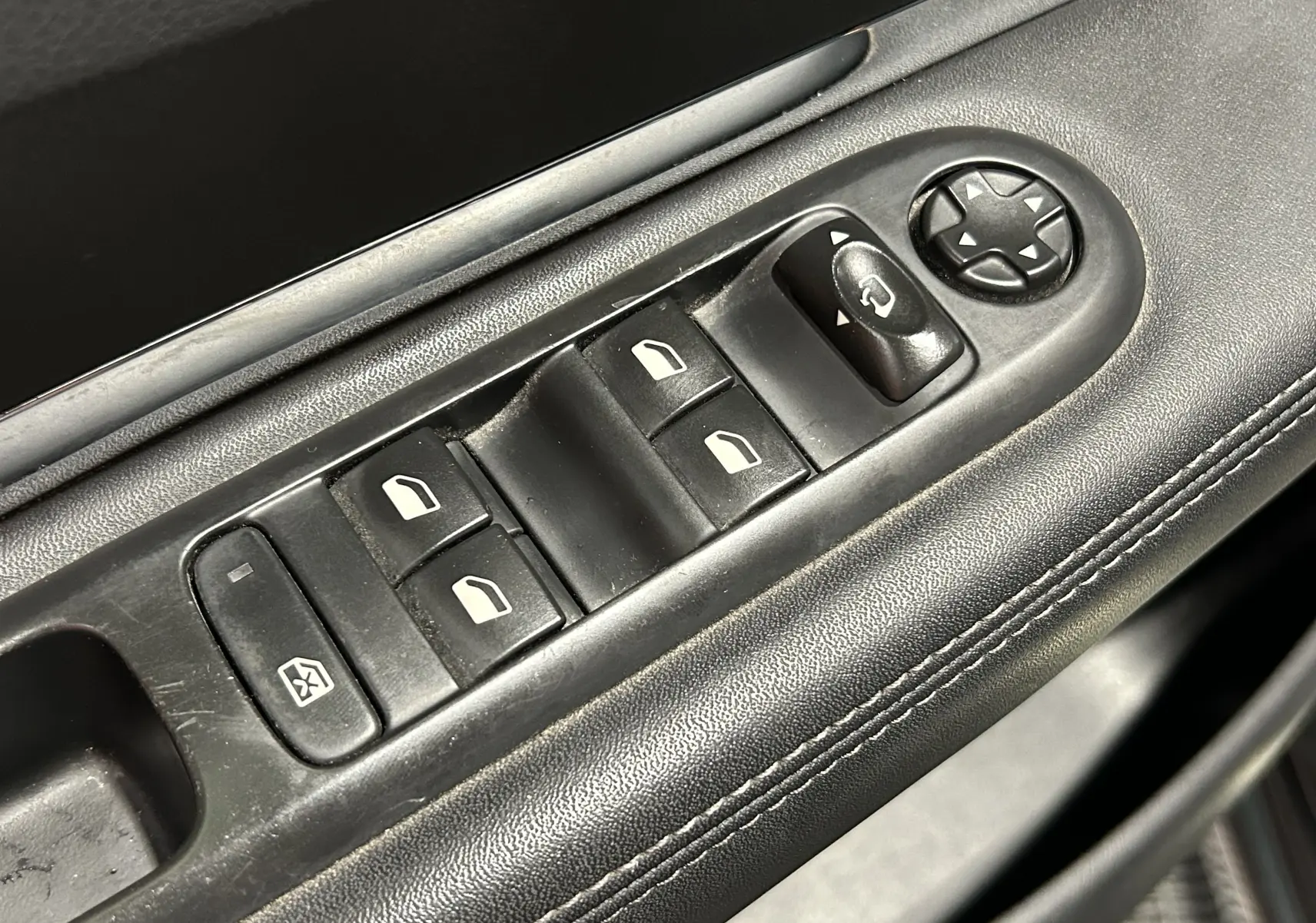Détail des commandes de lève-vitres et réglage des rétroviseurs sur la porte côté conducteur du Peugeot 3008 gris.