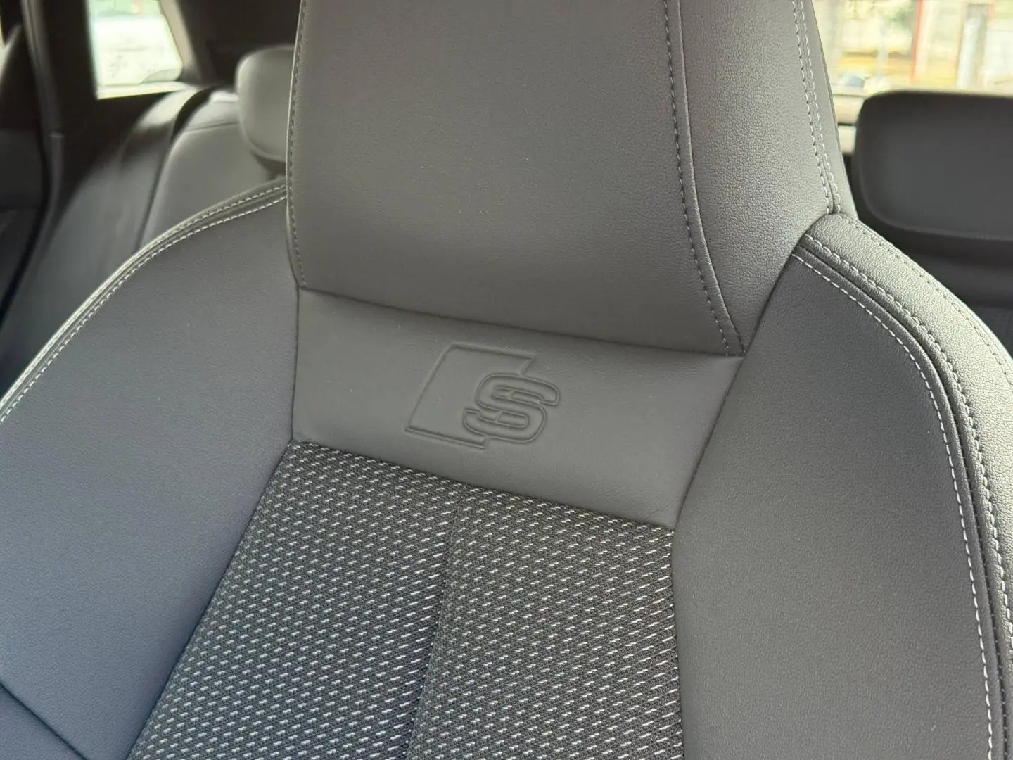Gros plan sur le siège avant sport gris avec logo S embossé, intérieur Audi A3 Sportback 2025.