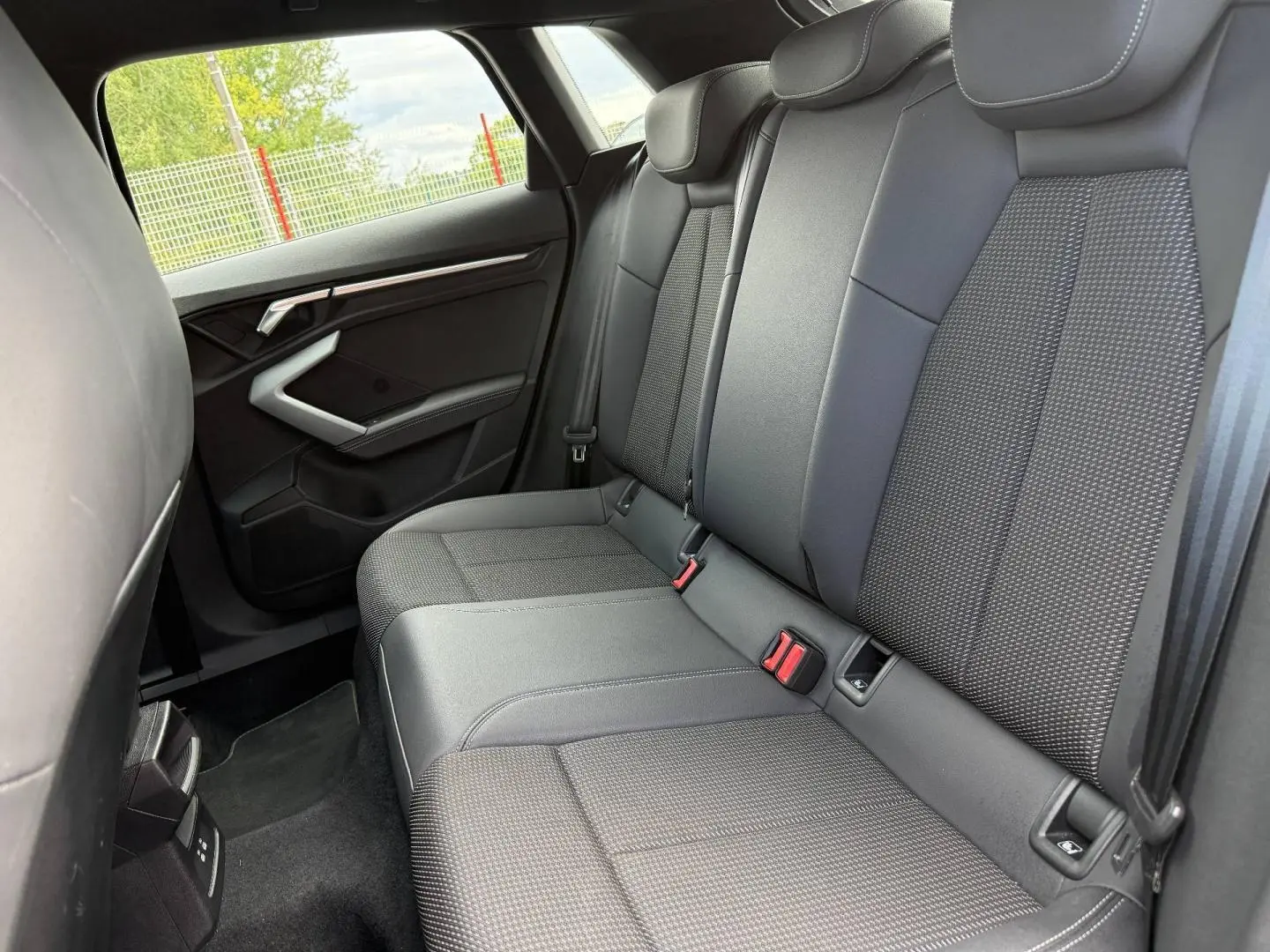 Vue latérale intérieure des sièges arrière en tissu noir et gris de l'Audi A3 Sportback 2025, version S line.