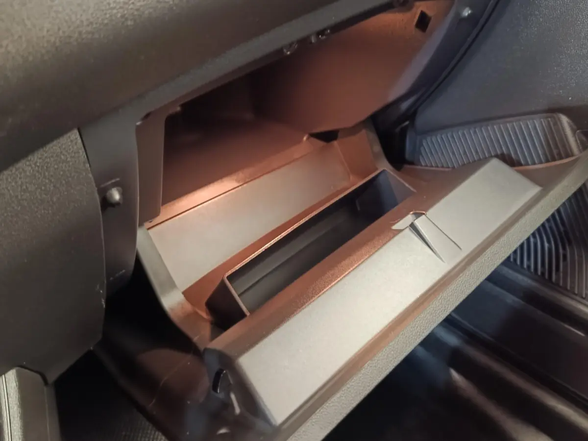Gros plan sur la boîte à gants ouverte de la Renault Express Confort blanche, intérieur noir mat.
