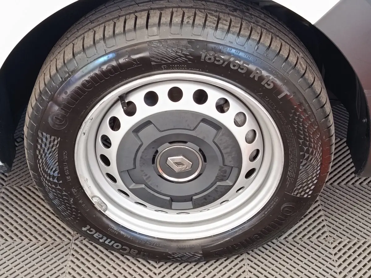 Gros plan sur la roue avant droite avec jante acier et logo Renault, partie blanche de la carrosserie visible.
