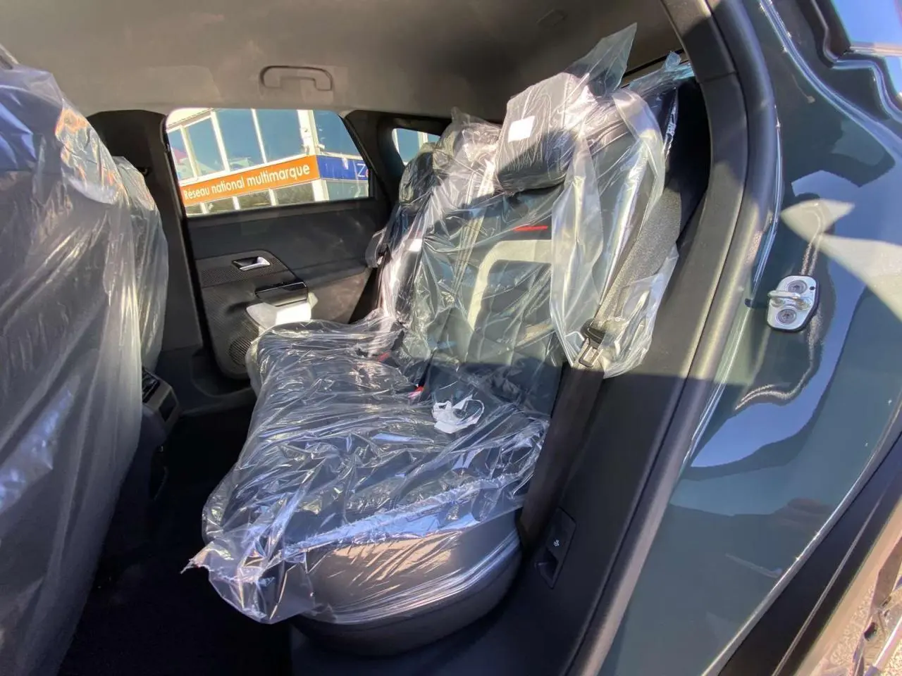 Vue intérieure côté droit des sièges arrière protégés par des housses plastiques sur un Citroën C5 Aircross vert.