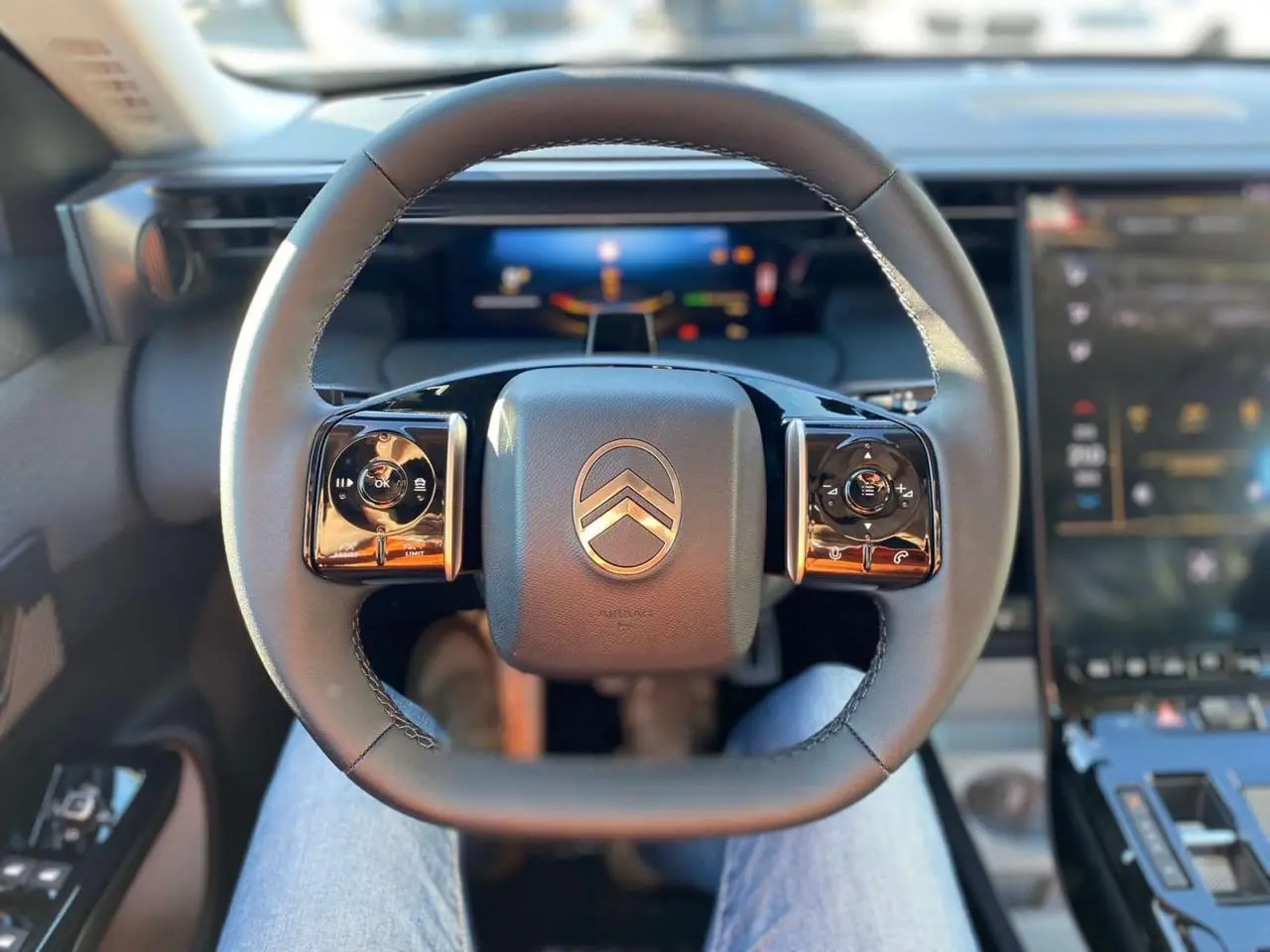 Vue intérieure centrée sur le volant du Citroën C5 Aircross 2026, avec commandes intégrées et tableau de bord numérique flou.
