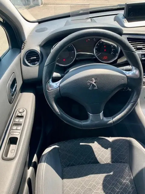 Vue intérieure du poste de conduite du Peugeot 3008 noir 2014, volant cuir avec logo lion et tableau de bord digital.