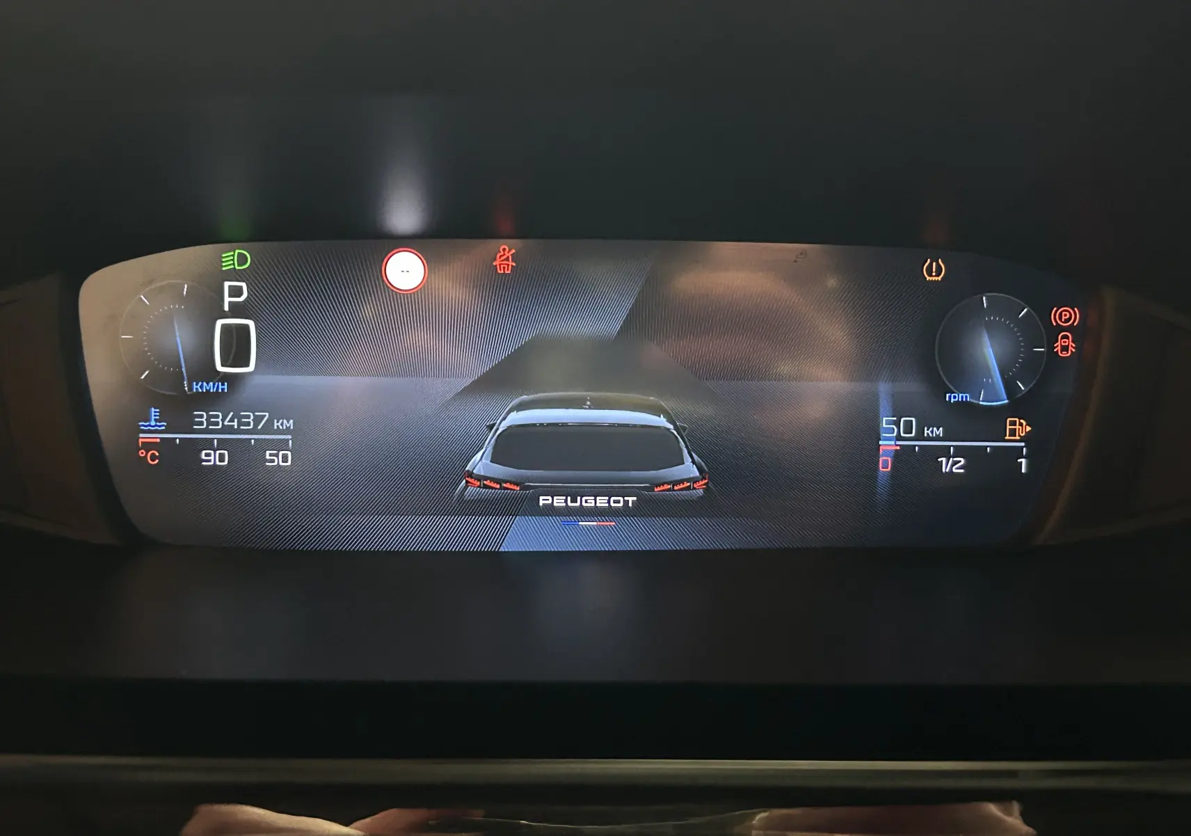 Affichage numérique du tableau de bord de la Peugeot 308 2024, montrant la voiture vue de l'arrière et les indicateurs de vitesse, température et carburant.