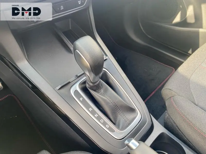 Gros plan sur le levier de vitesses automatique en cuir noir de la Ford Puma gris Cactus, avec coutures rouges visibles.