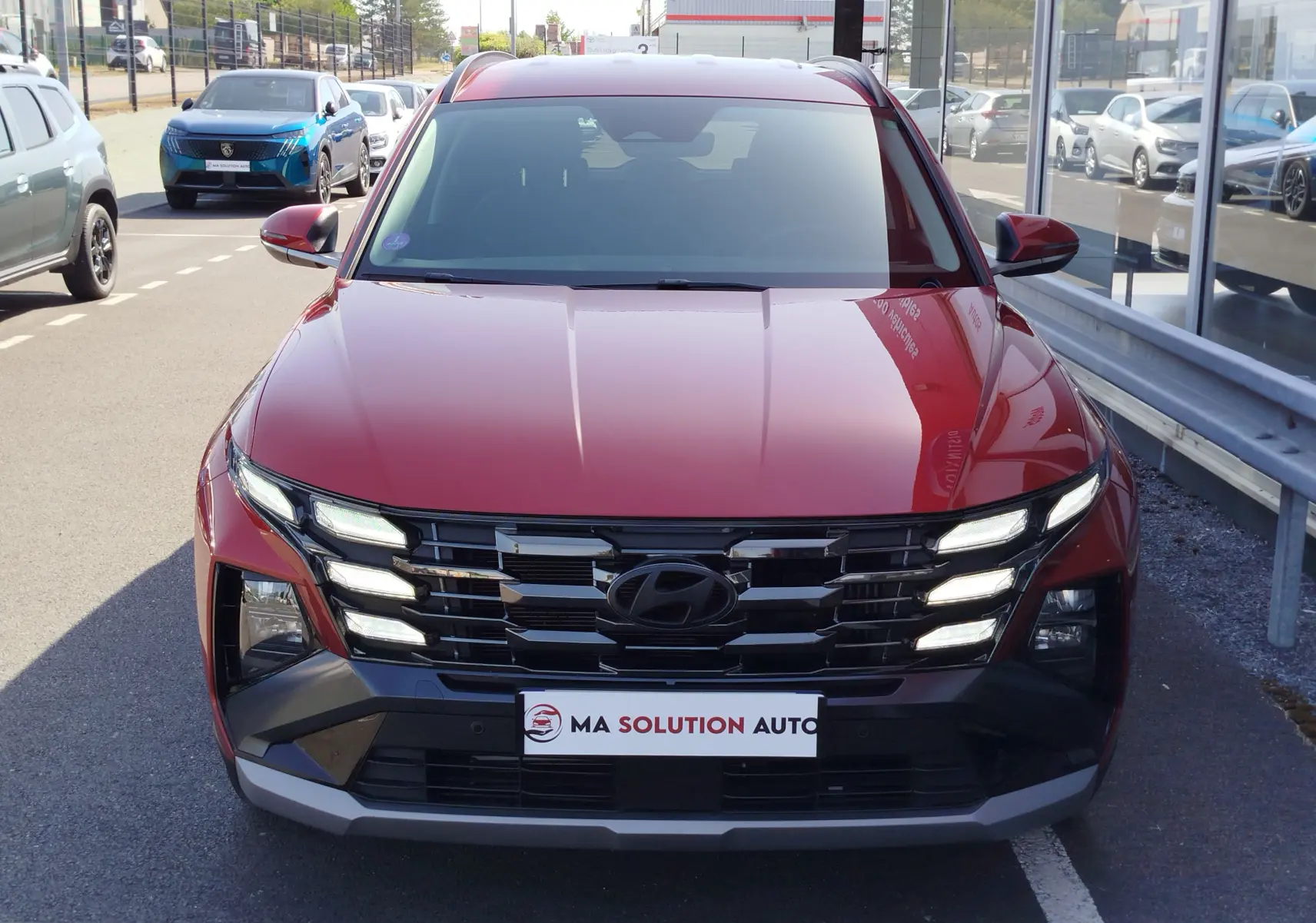 Vue de face du Hyundai Tucson 2024 en rouge Ultimate Métal, mettant en valeur sa calandre noire et ses feux LED distinctifs.