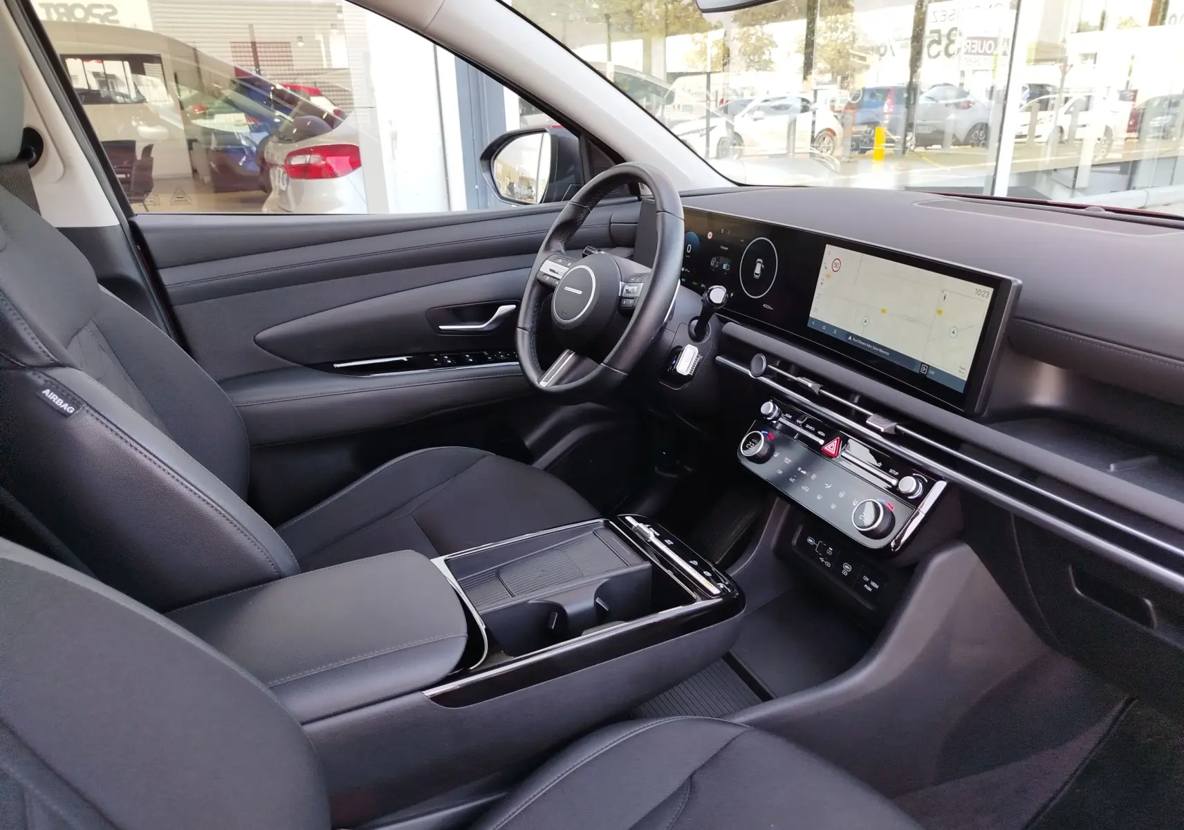 Vue intérieure côté conducteur du Hyundai Tucson 2024, tableau de bord moderne avec écran tactile et sellerie noire.