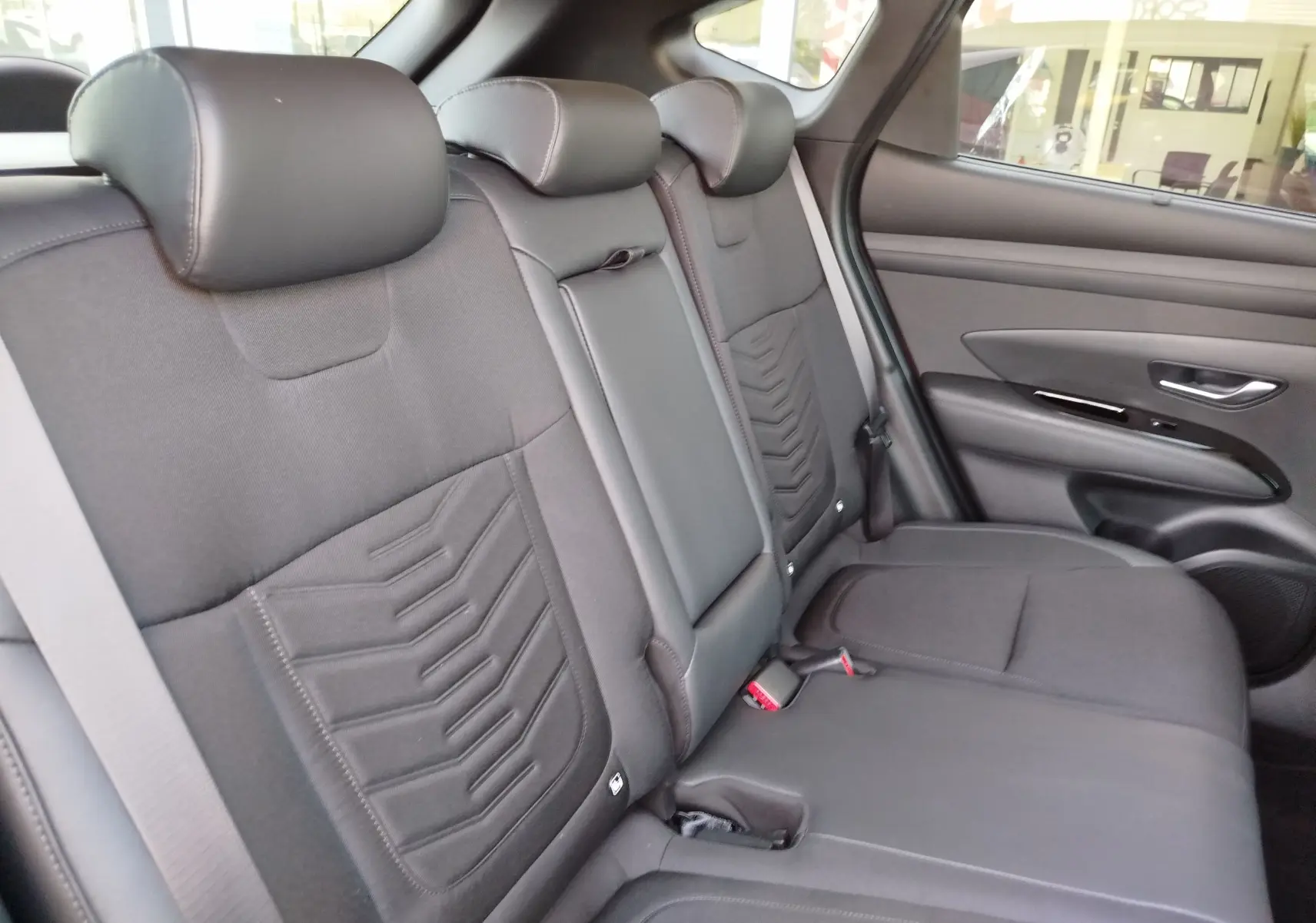 Vue intérieure côté droit des sièges arrière en tissu gris foncé du Hyundai Tucson 2024 version hybride.