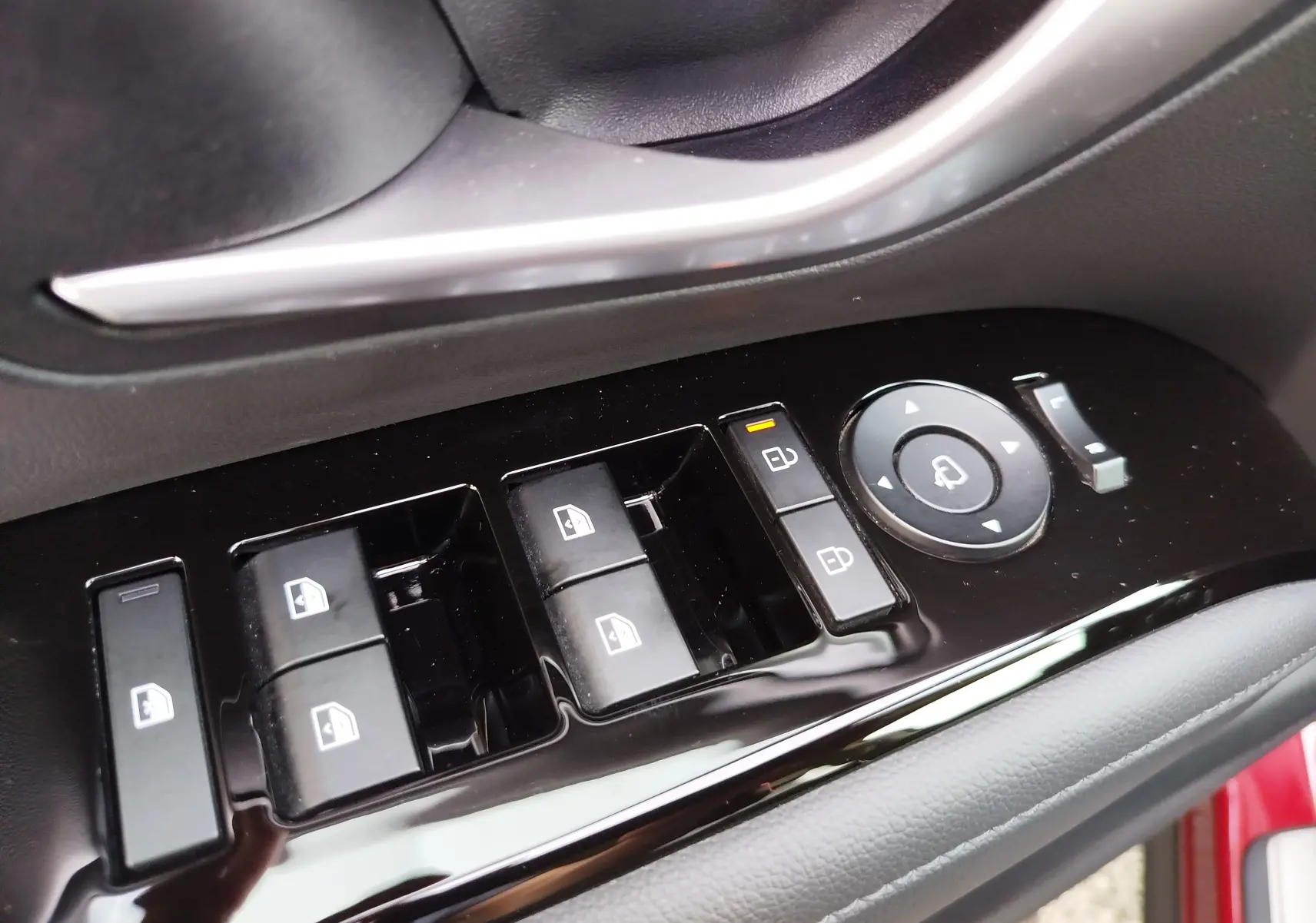 Gros plan sur les commandes de lève-vitres et rétroviseurs côté conducteur du Hyundai Tucson 2024 en rouge Ultimate Red Métal.