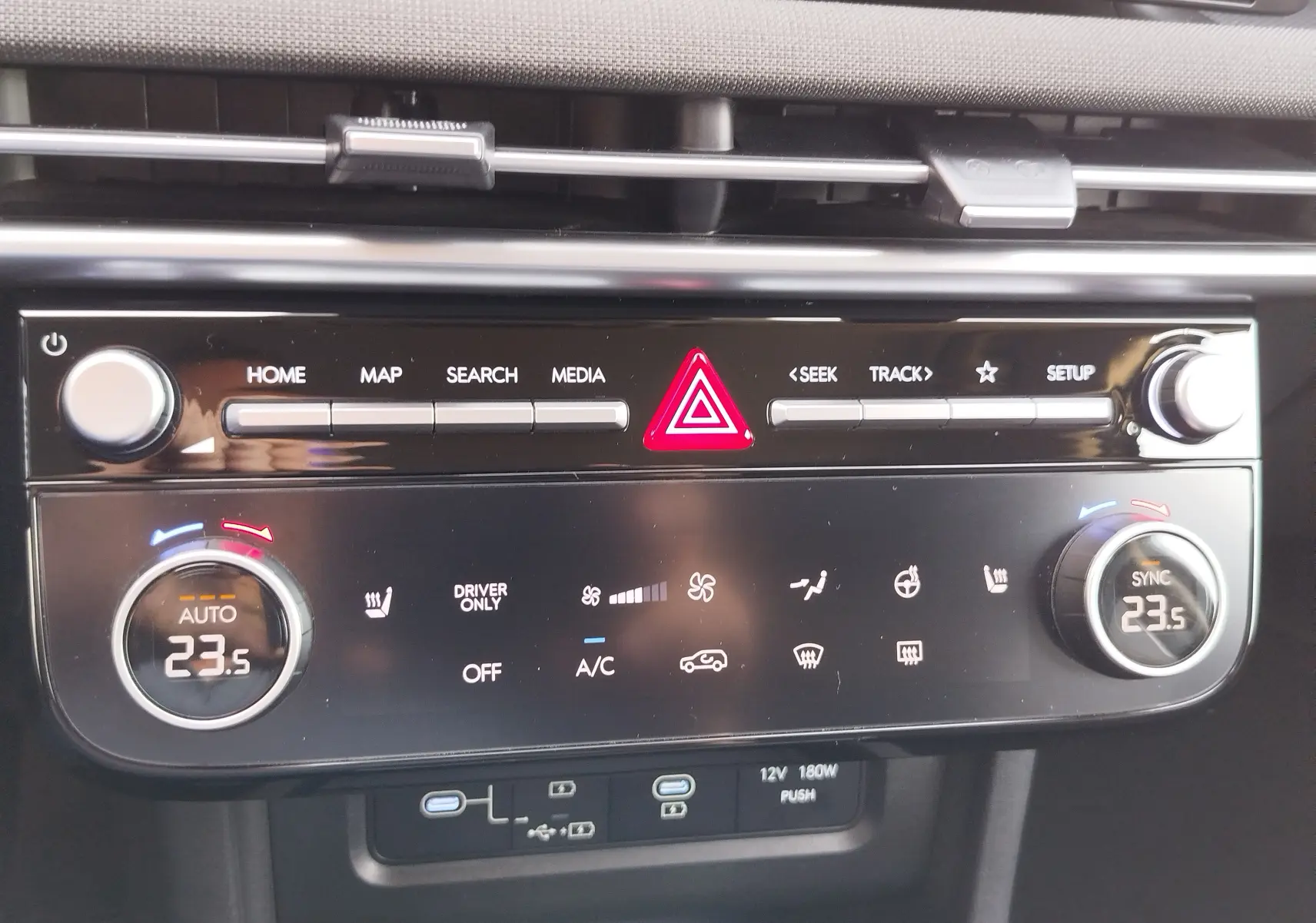 Vue rapprochée de la console centrale du Hyundai Tucson 2024, affichant les commandes de climatisation et multimédia.