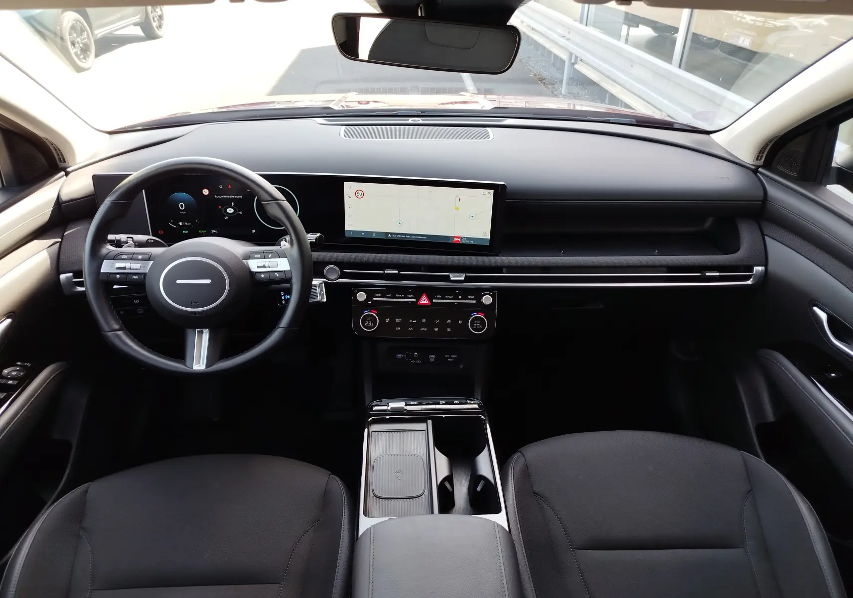Vue intérieure avant du Hyundai Tucson 2024, tableau de bord noir avec écran tactile et volant multifonction.