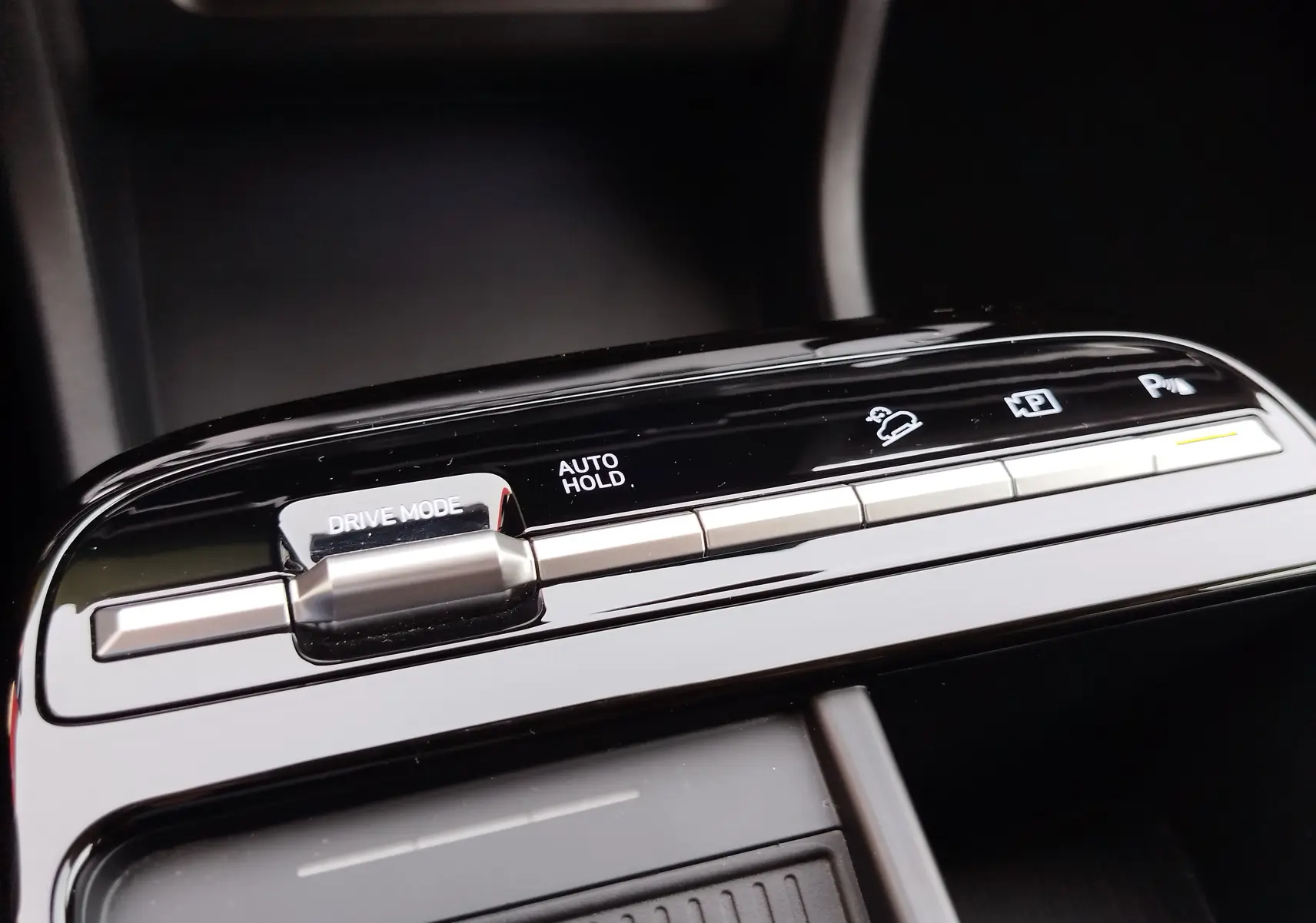 Gros plan sur les commandes de la console centrale du Hyundai Tucson 2024, finition noire brillante avec boutons argentés.