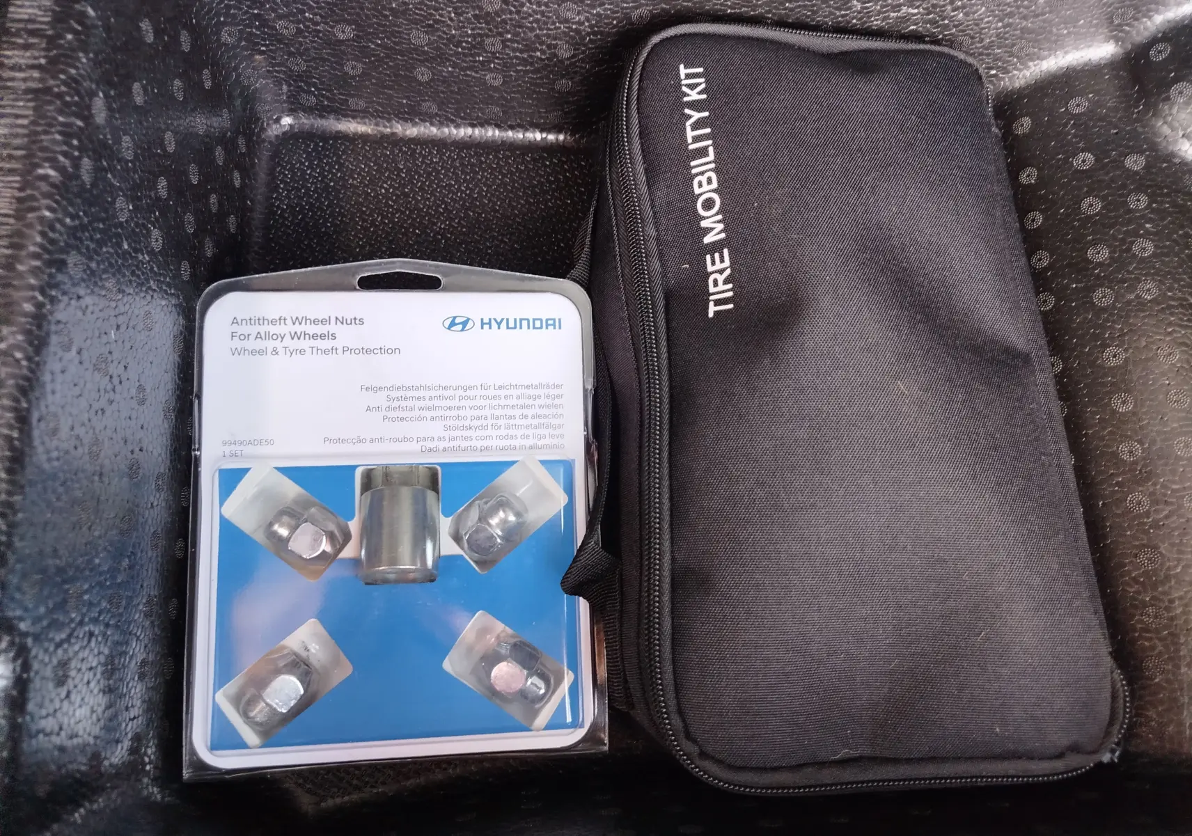 Vue rapprochée du kit anti-vol de boulons de roue Hyundai et d’une trousse noire Tire Mobility Kit dans le coffre.