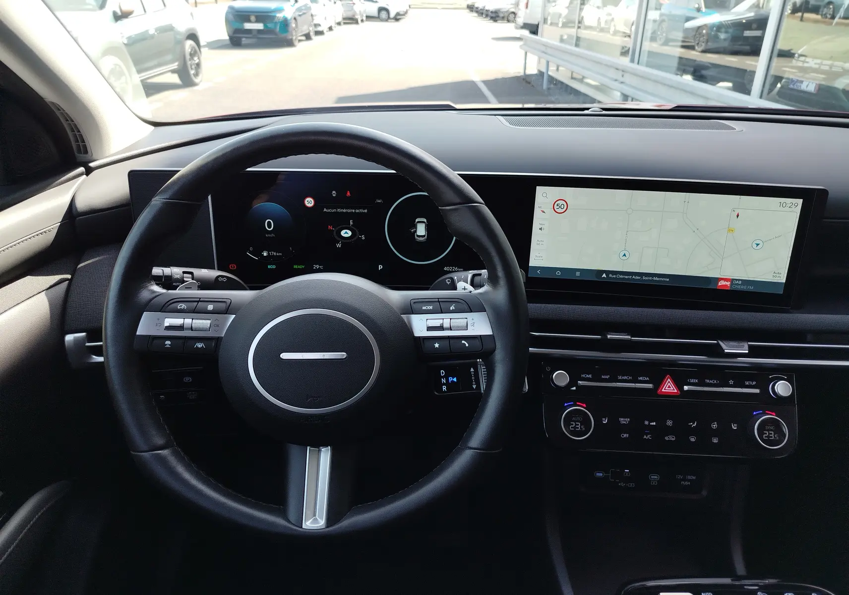 Vue intérieure du tableau de bord du Hyundai Tucson 2024, avec volant noir et double écran numérique affichant navigation et informations.