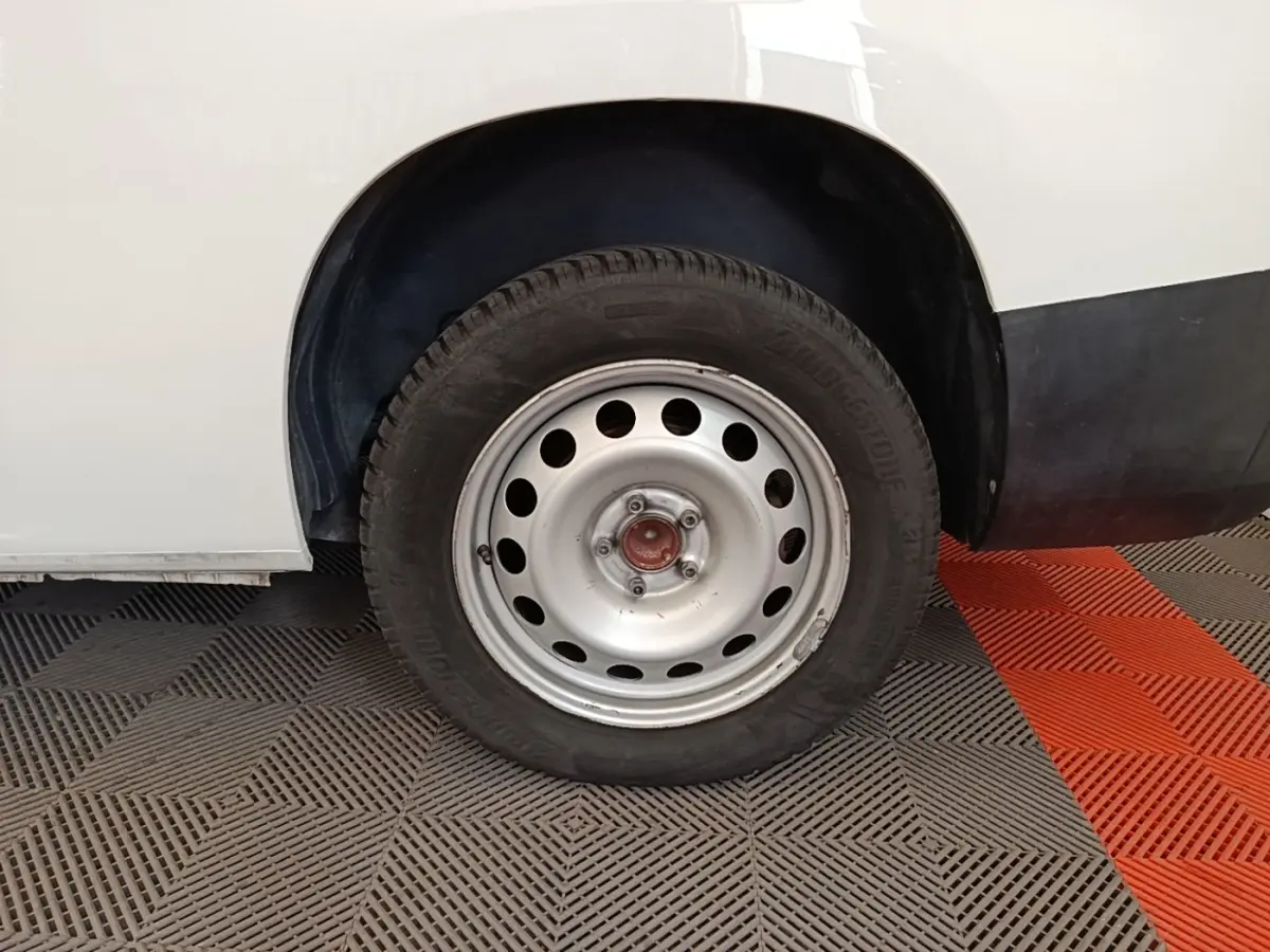 Gros plan sur la roue arrière droite en jante acier du Citroën Berlingo XL blanc, partie basse de la carrosserie visible.