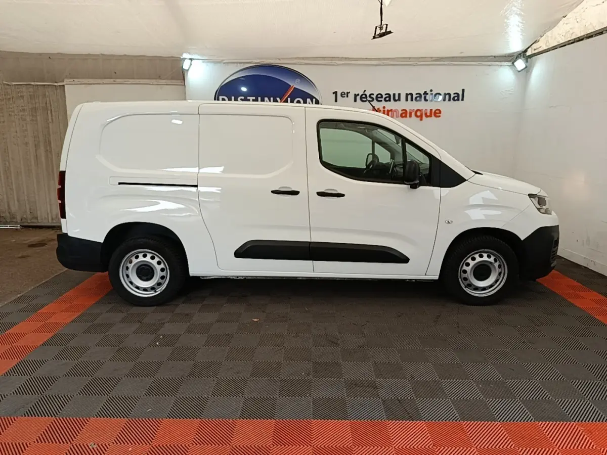 Vue de profil côté droit d'un utilitaire Citroën Berlingo XL blanc avec protections latérales noires et jantes acier.