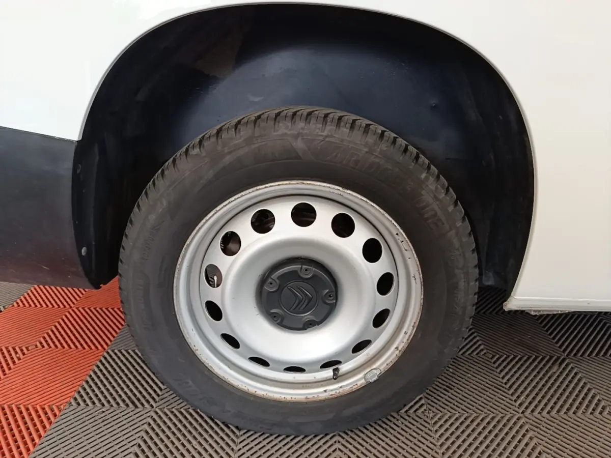 Gros plan sur la roue avant gauche d’un Citroën Berlingo blanc avec jante acier et logo Citroën central.