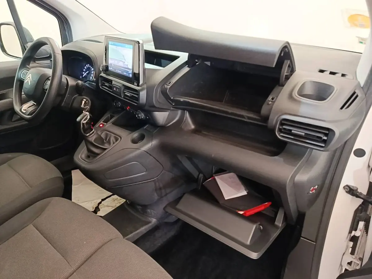Vue intérieure côté passager du Citroën Berlingo XL blanc, montrant tableau de bord et rangements ouverts.