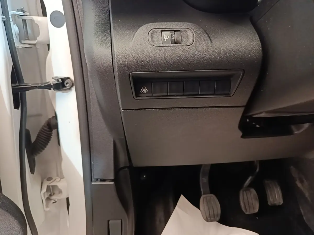 Détail intérieur côté conducteur du Citroën Berlingo XL blanc 2020, montrant les pédales et commandes sous le tableau de bord.